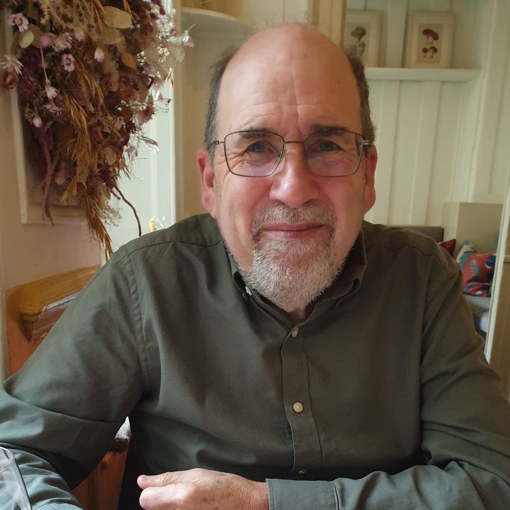 A man wearing glasses and smiling.
