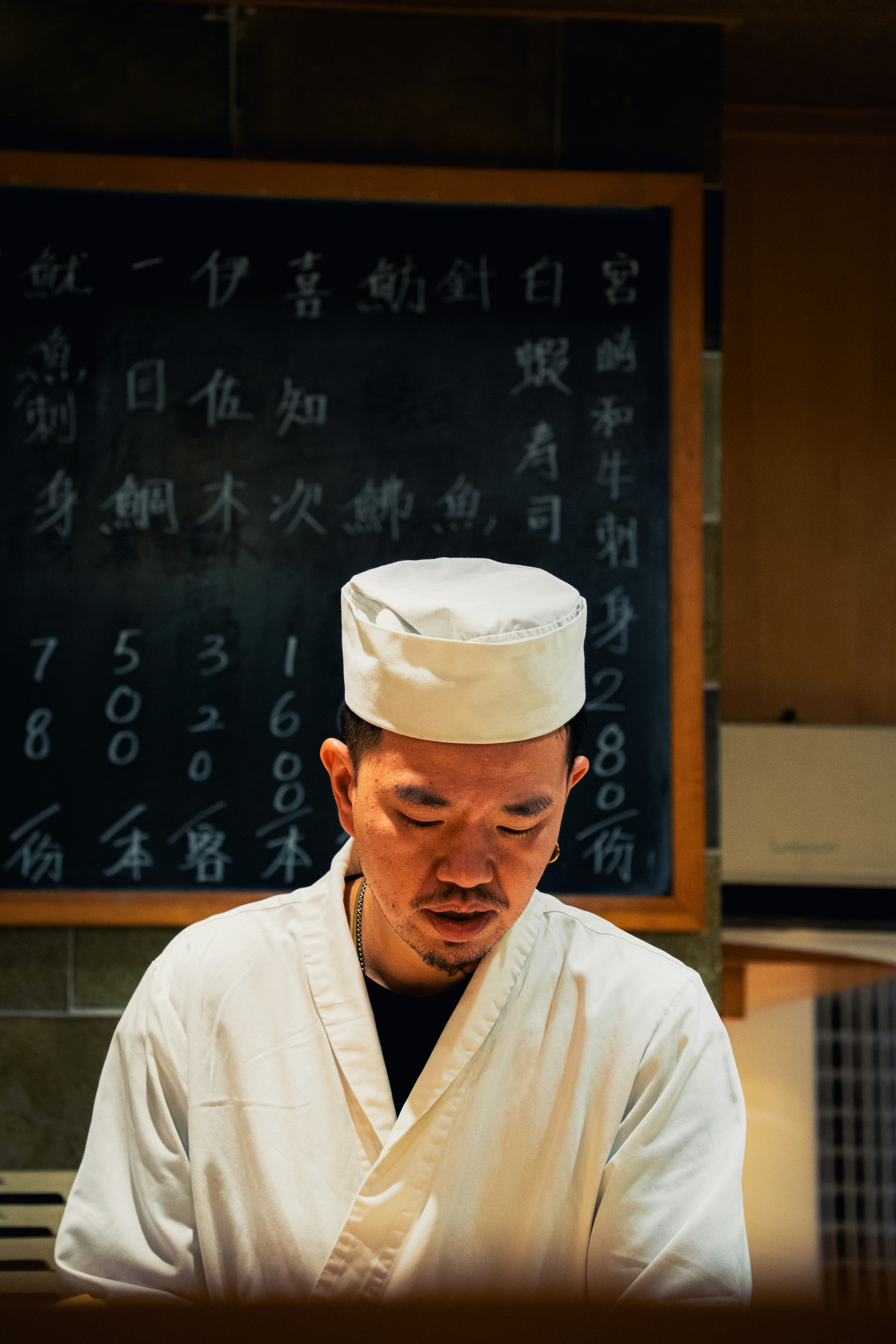 a man in a chef's outfit standing in front of a blackboard