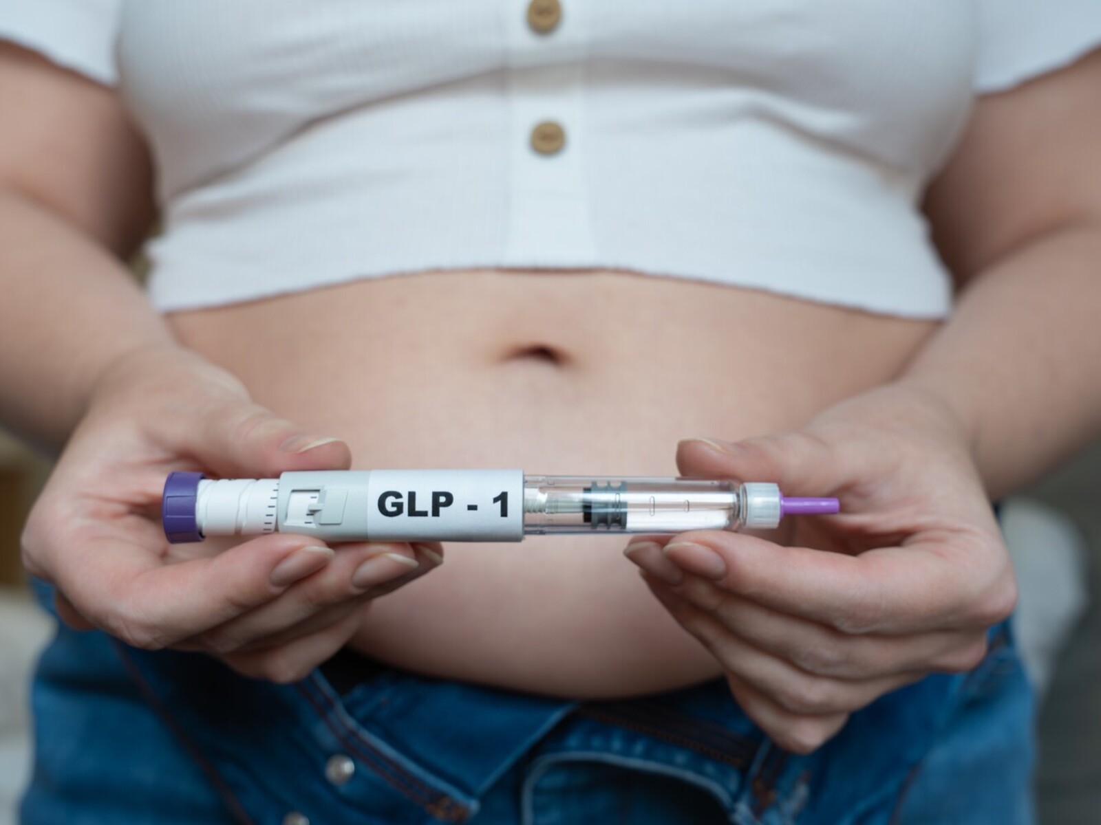 woman holding a GLP-1 option for the best weight loss shot in front of her stomach