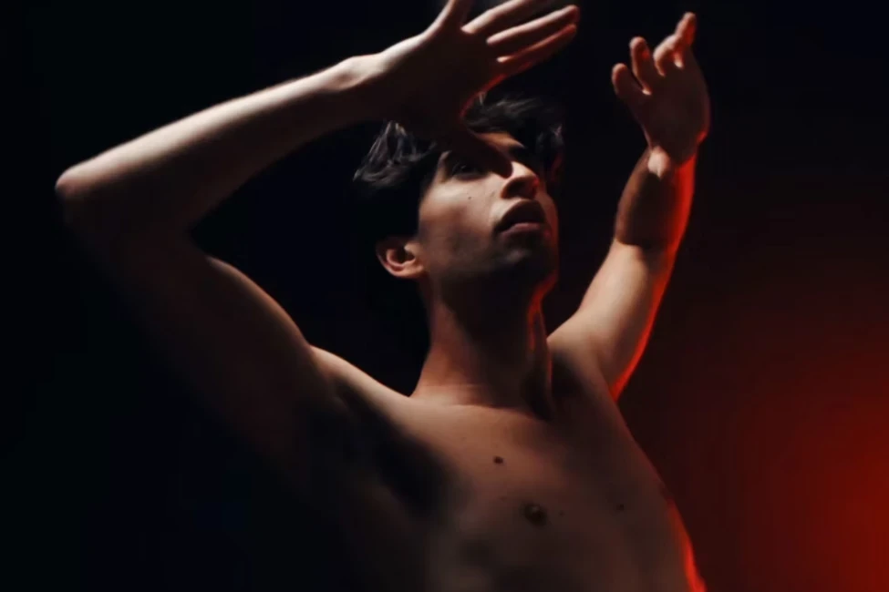 A male dancing in front of a red light