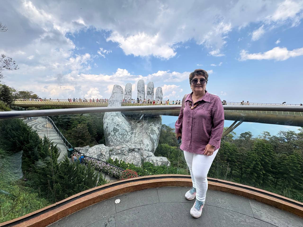 person in orange jacket standing on brown rock near snow covered mountain during daytime