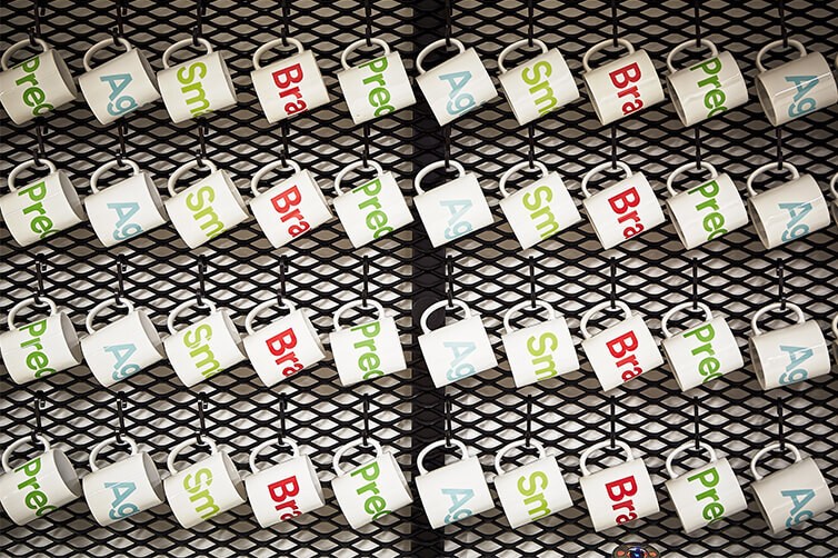 Wall display of branded mugs hanging in rows