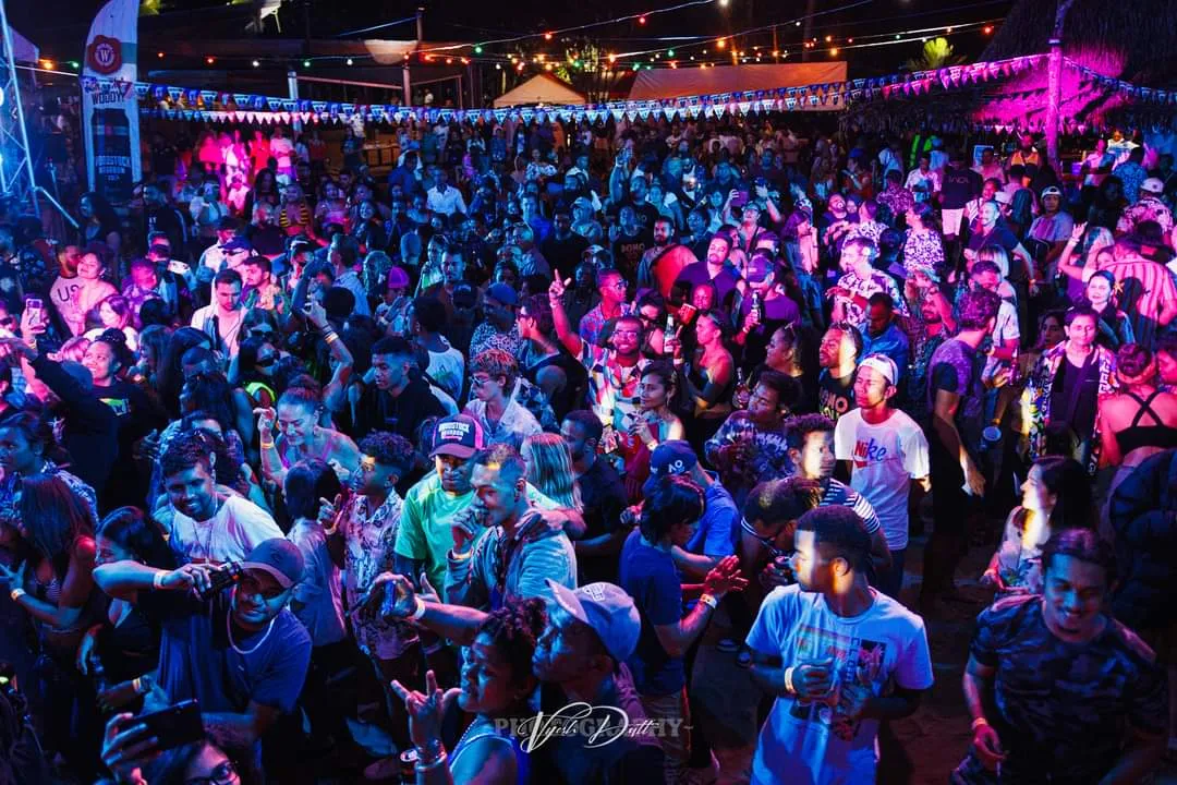 A crowd of people celebrating at a music festival on the beach in Fiji