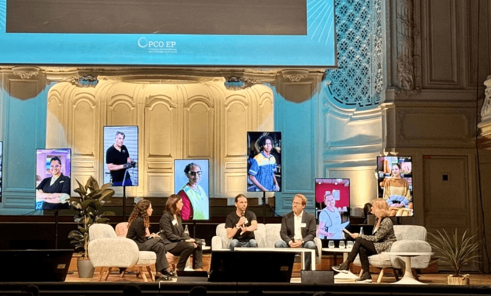 Film clapperboard in focus with glowing orange background, misty street, and silhouettes of people and lights; conveys mystery and anticipation.