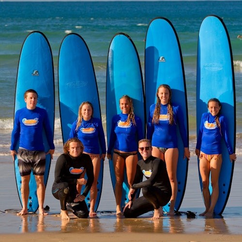 Litrato ng grupo ng mga matagumpay na surfer matapos ang aralin sa pag-surf.