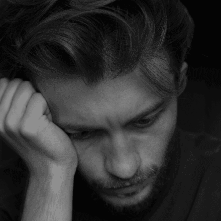 Man resting his head on his hand, reflecting feelings of sadness and the support offered by HeadHealth mental health services.