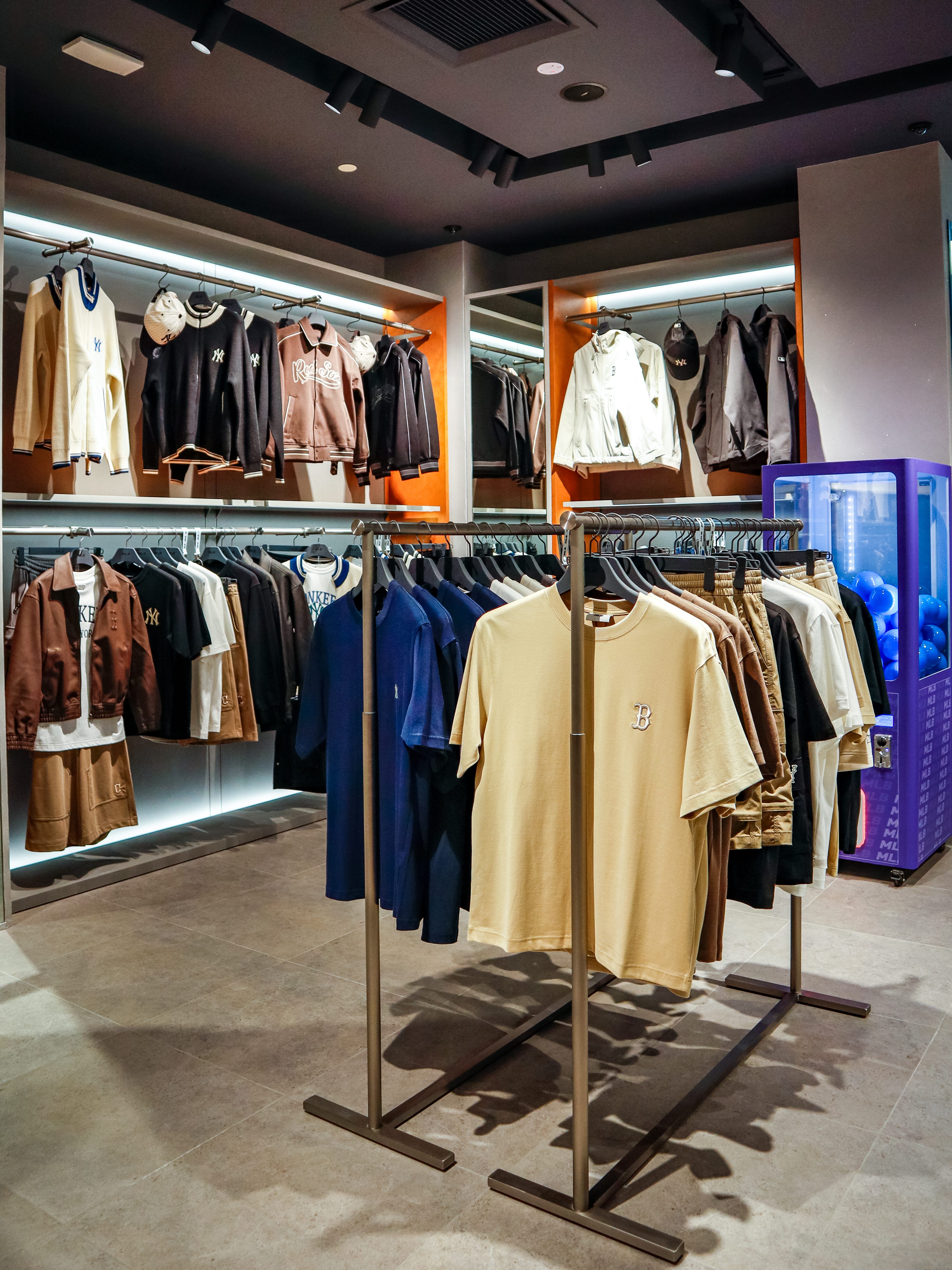 Interior view of the MLB 2.0 concept store showcasing clothing racks filled with various apparel including shirts and jackets, highlighting a modern and stylish design.