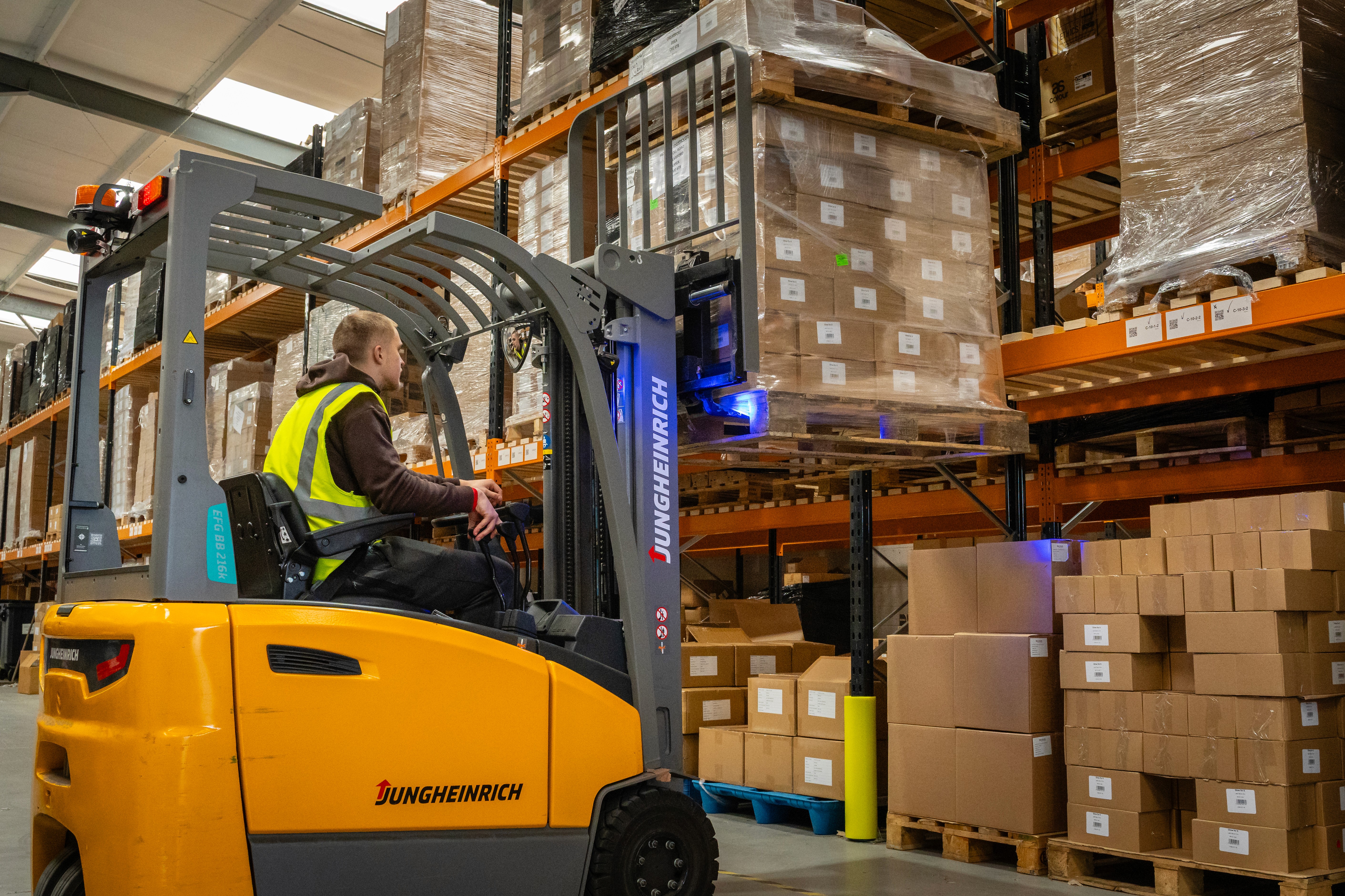 photo of someone on a forklift putting a pallet onto racking