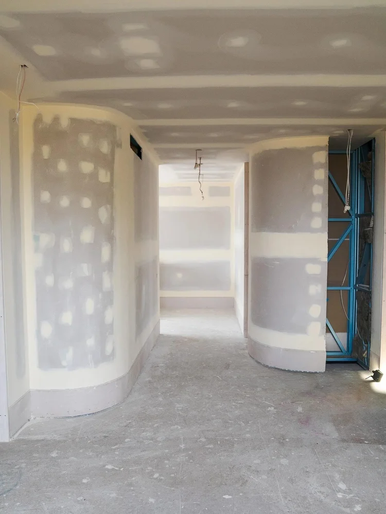 Unfinished hallway construction with exposed drywall and wiring.