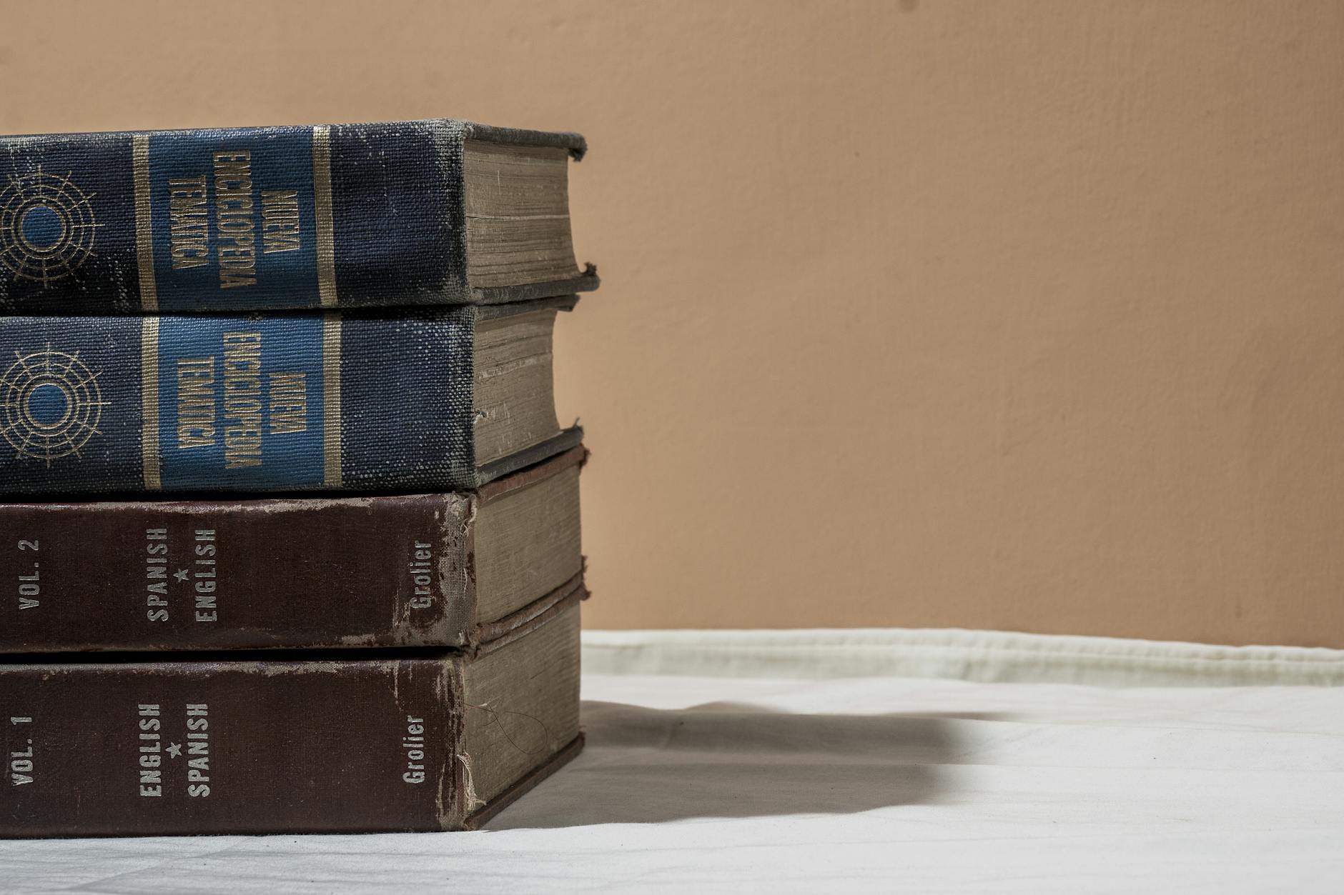 A group of elementary students gather around an open encyclopedia about space and planets in a bright library.