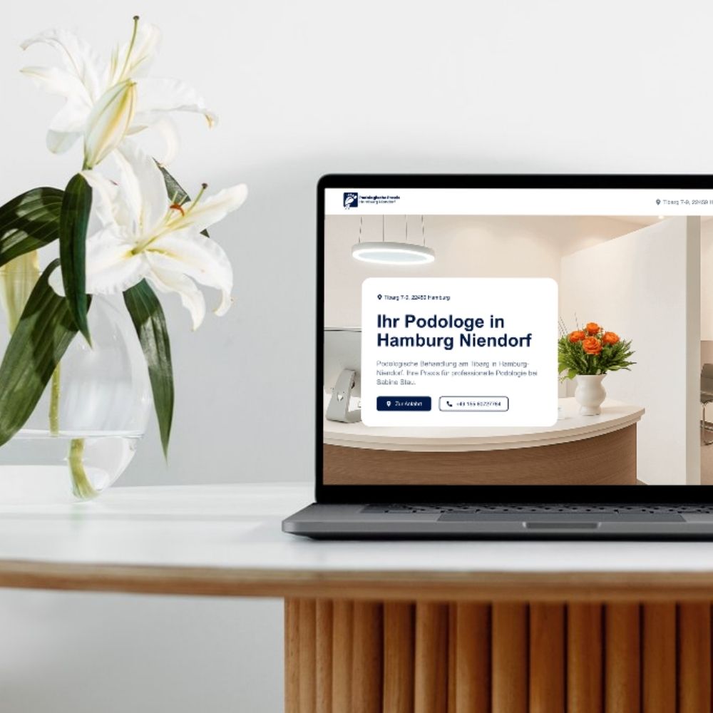 Two colleagues collaborating at a desk, looking at a laptop screen and discussing something with interest.