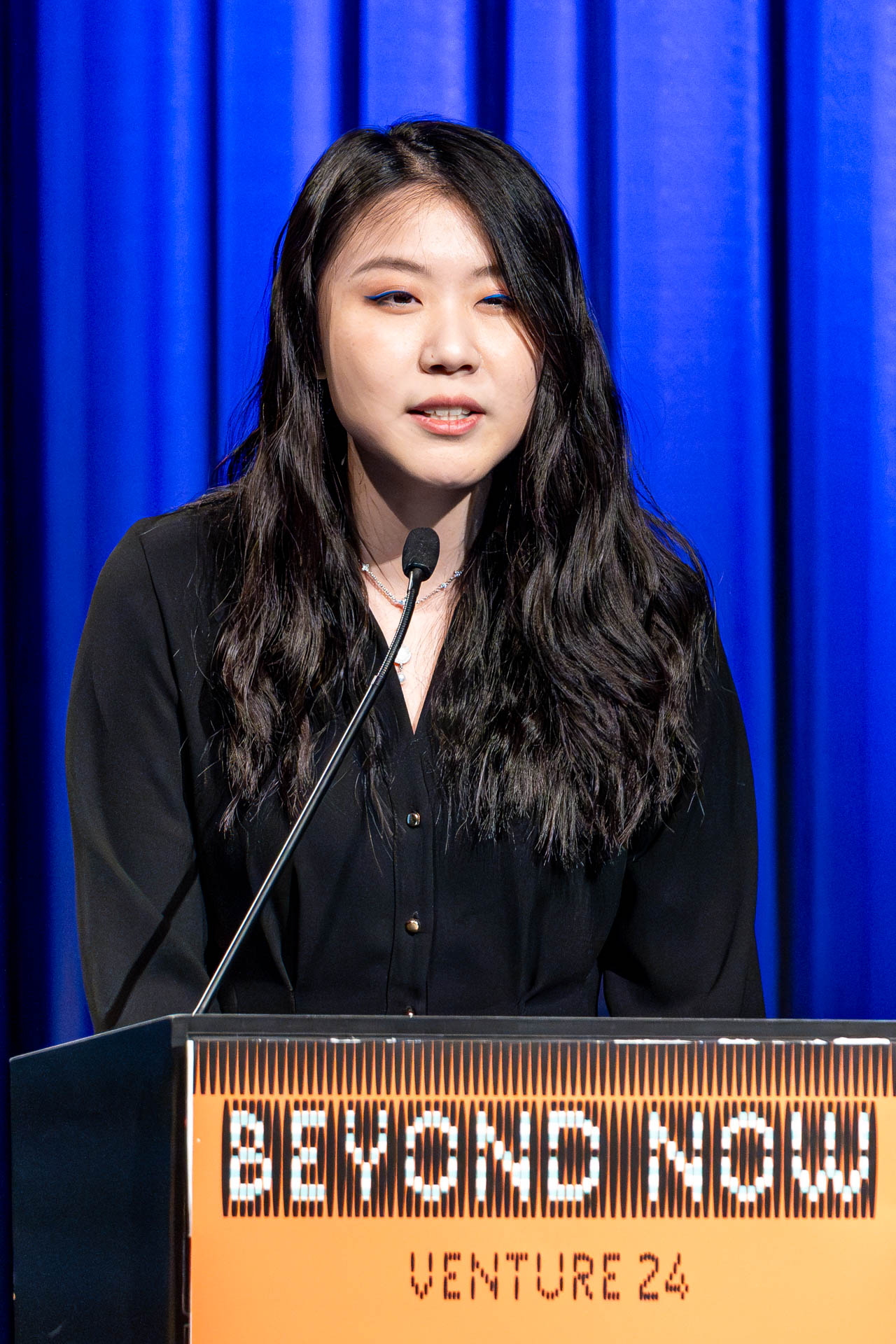 a student at a podium presenting a project in a Theatre