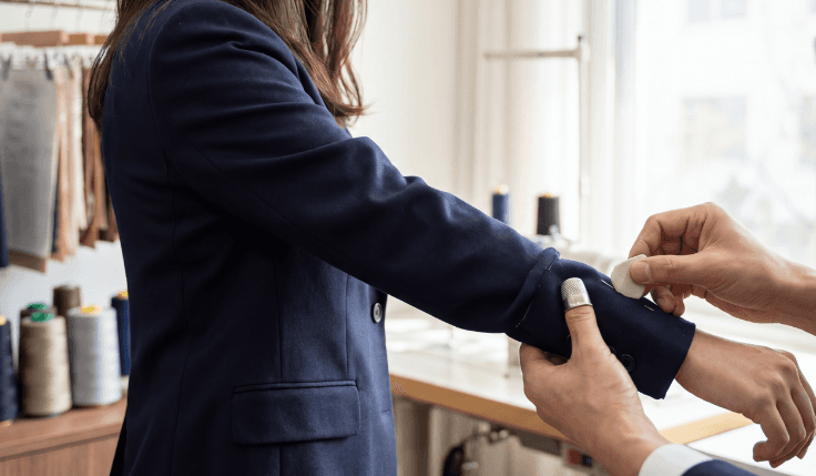 Woman having a tailored navy suit fitted by a tailor.