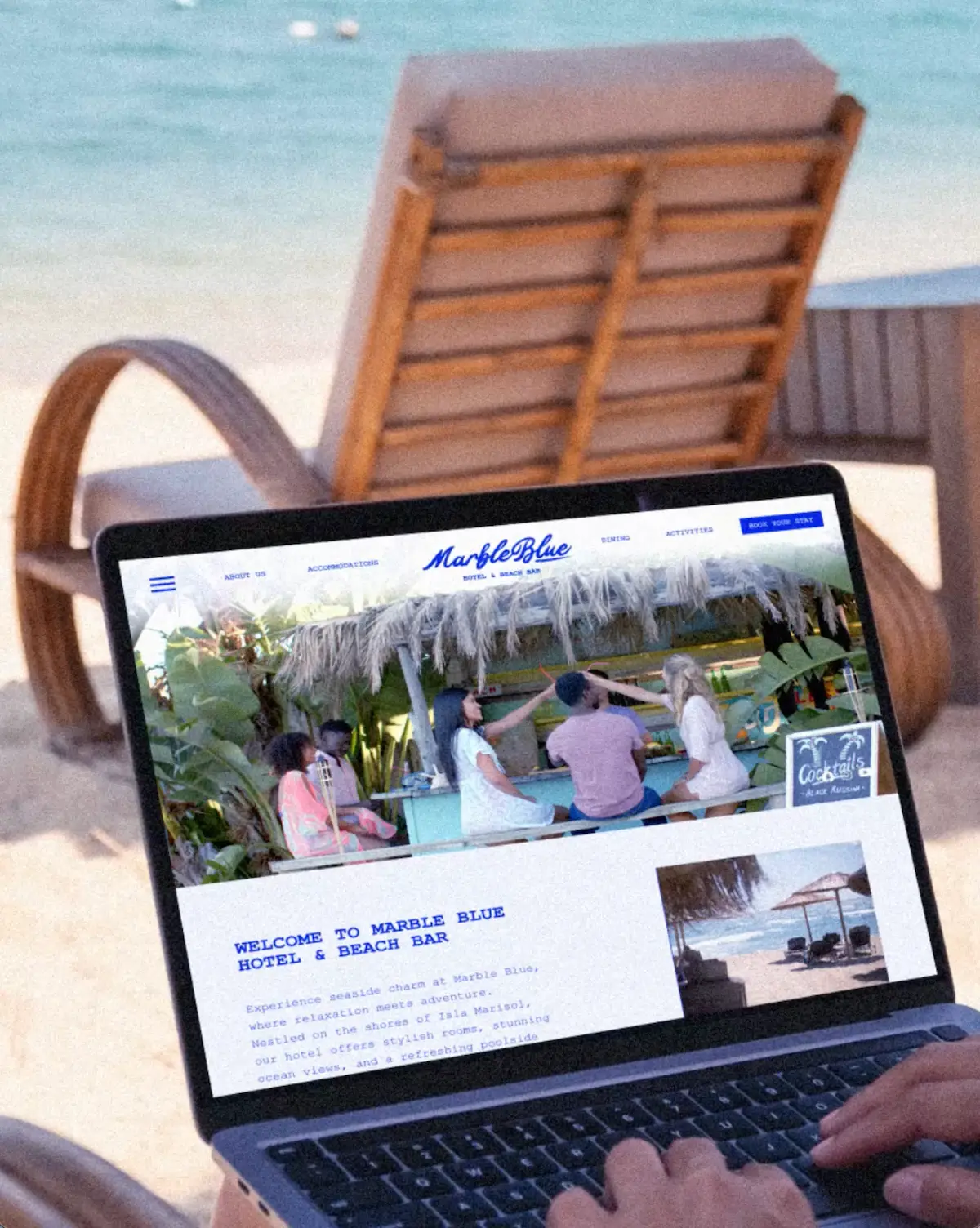 Mockup du site web Marble Blue ouvert sur MacBook posé sur le sable en bord de mer, montrant la page d'accueil avec hero photo et texte de bienvenue.