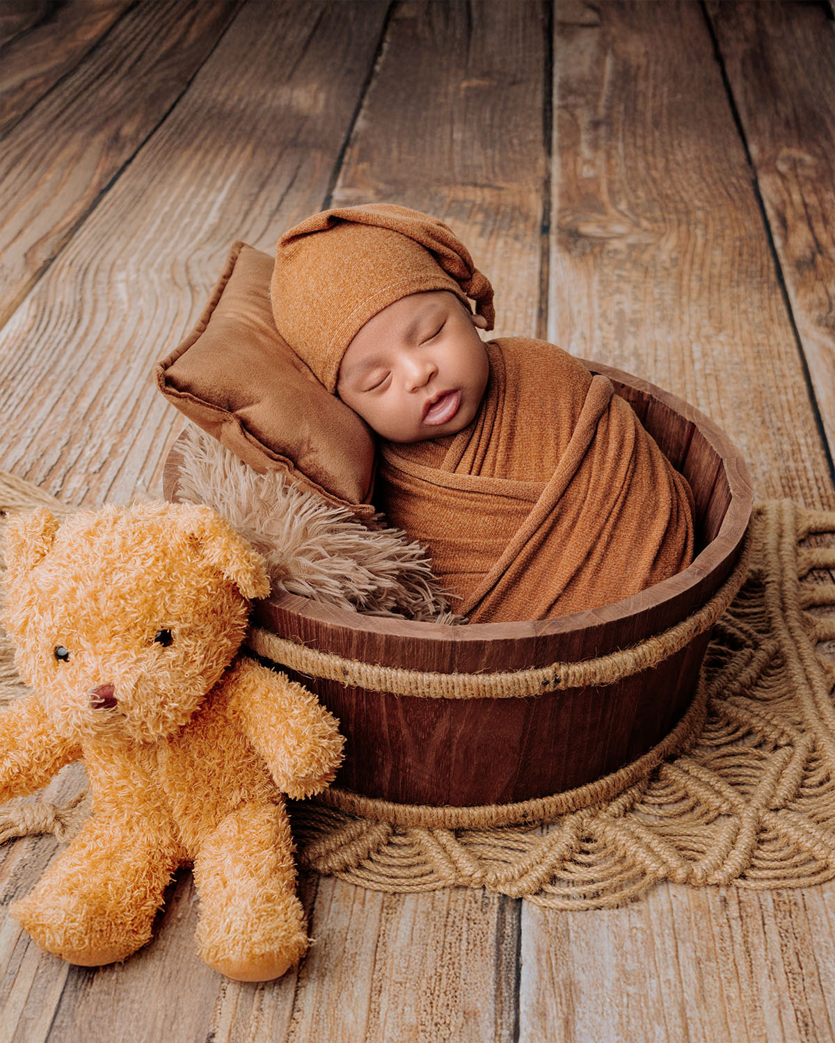 Newborn baby sleeping in basket with warm beige blanket setup.