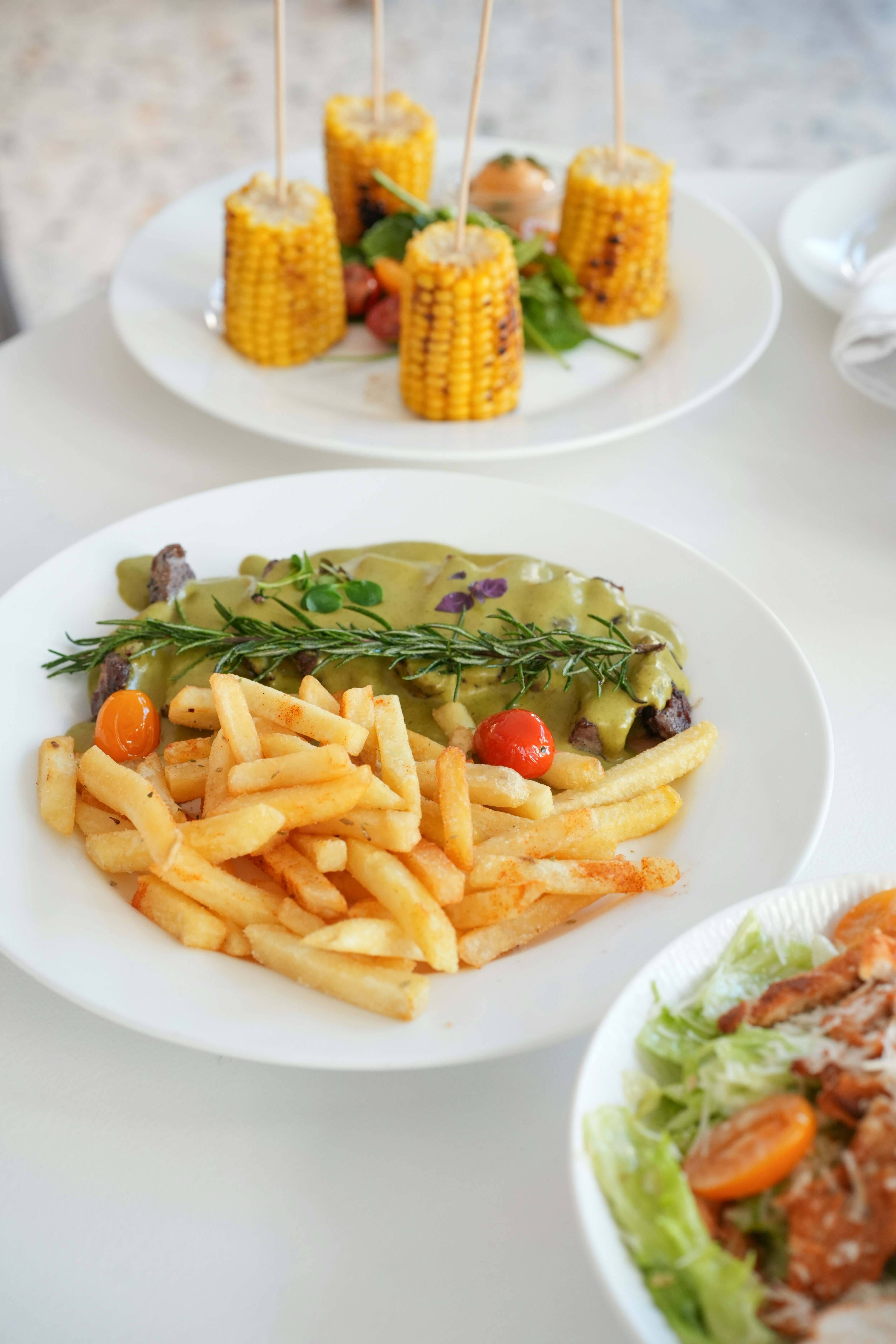 Delicious steak, fries, and corn on the cob.