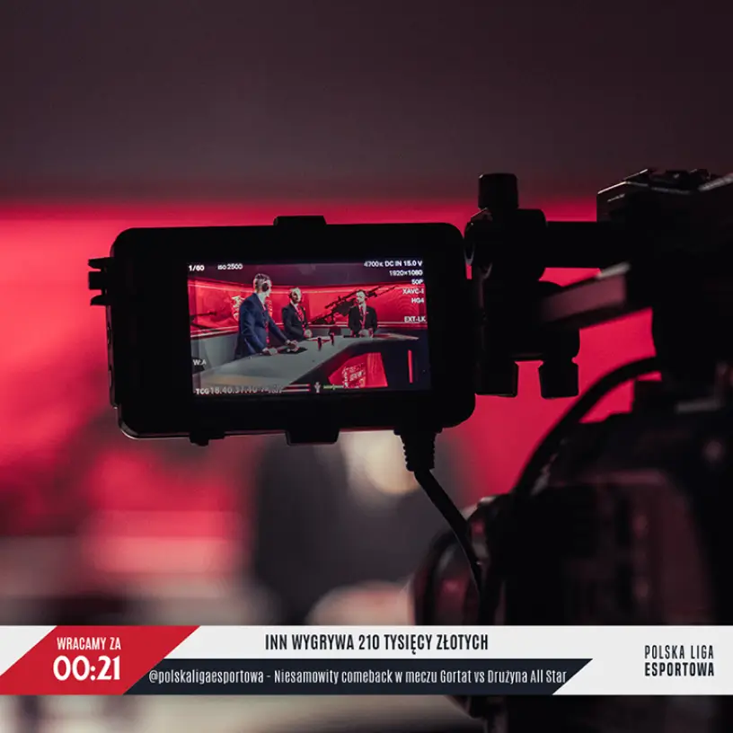 Kamera filmująca ekran ze studiem transmisji e-sportowej w czerwonej scenografii