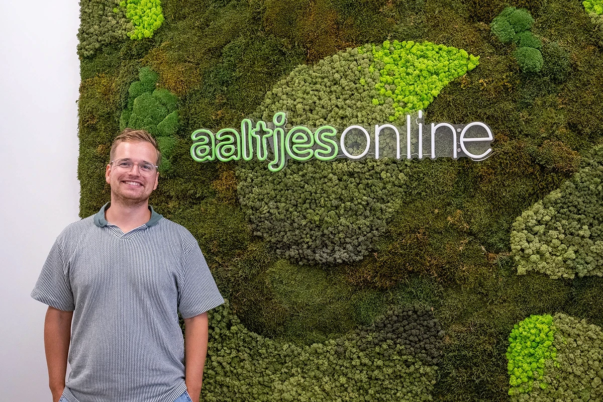 Medewerker van Aaltjes Online voor een mosmuur met het bedrijfslogo