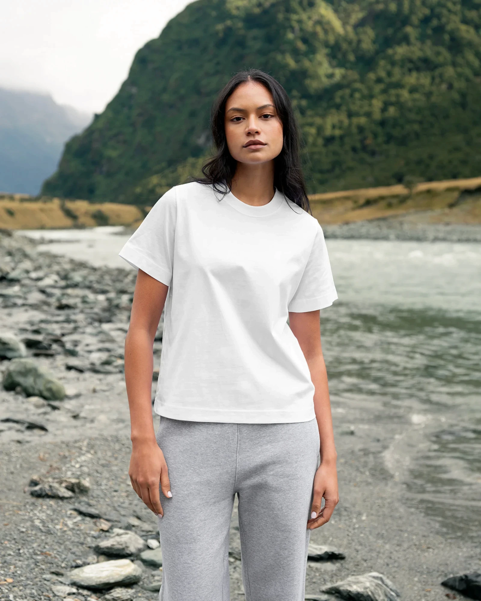 Woman in a plain white tee standing by a river