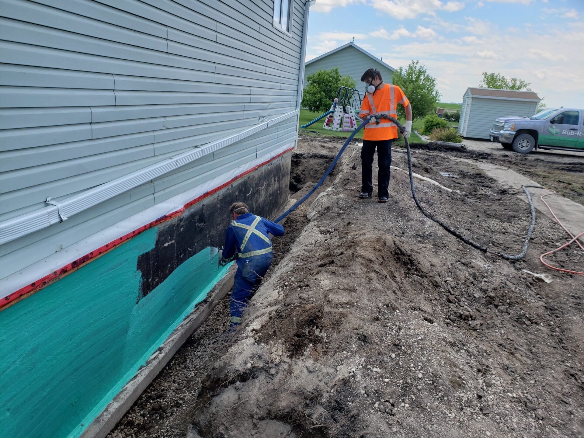 un technicien applique Rub-R-Wall à un fondement de sous-sol