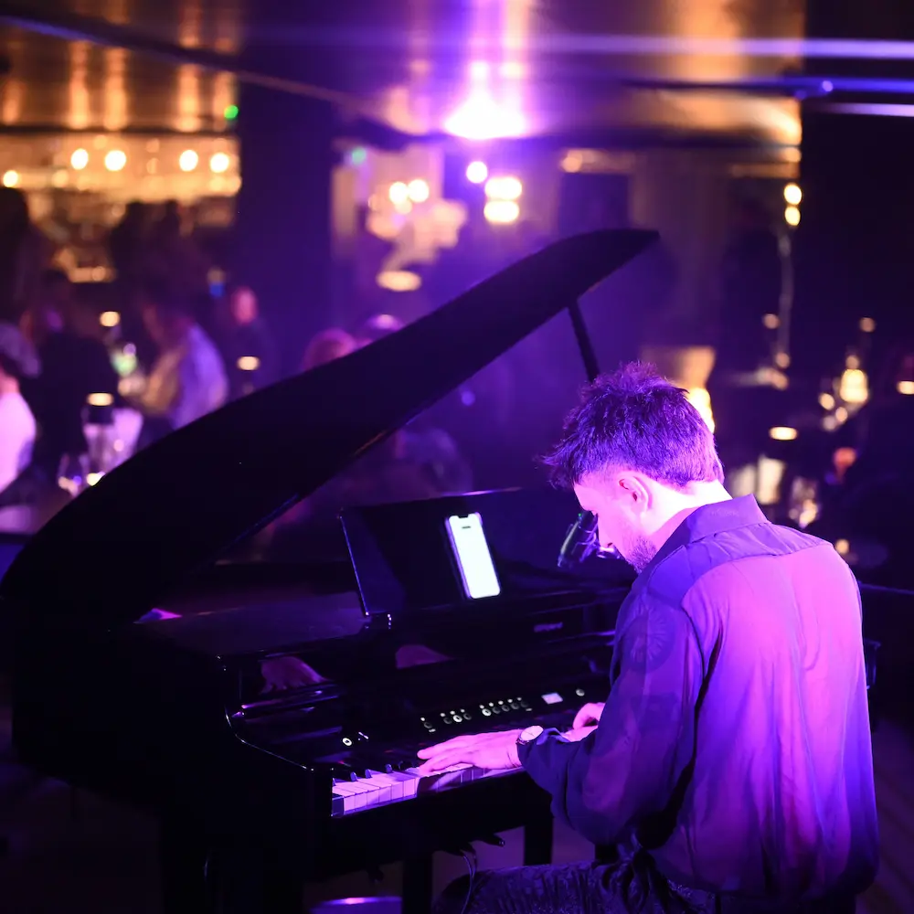 A virtuoso pianist and singer performing under warm spotlights in an elegant, intimate setting.