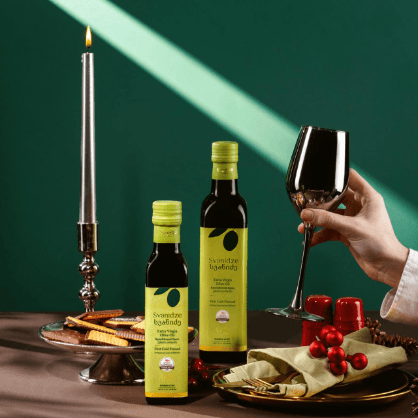 Smiling young man with short hair poses against a dark background, wearing a green button-up shirt.