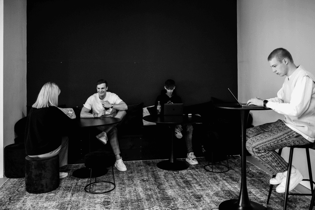 Flatline Agency team members working on laptops in a lounge area of the office, in black and white