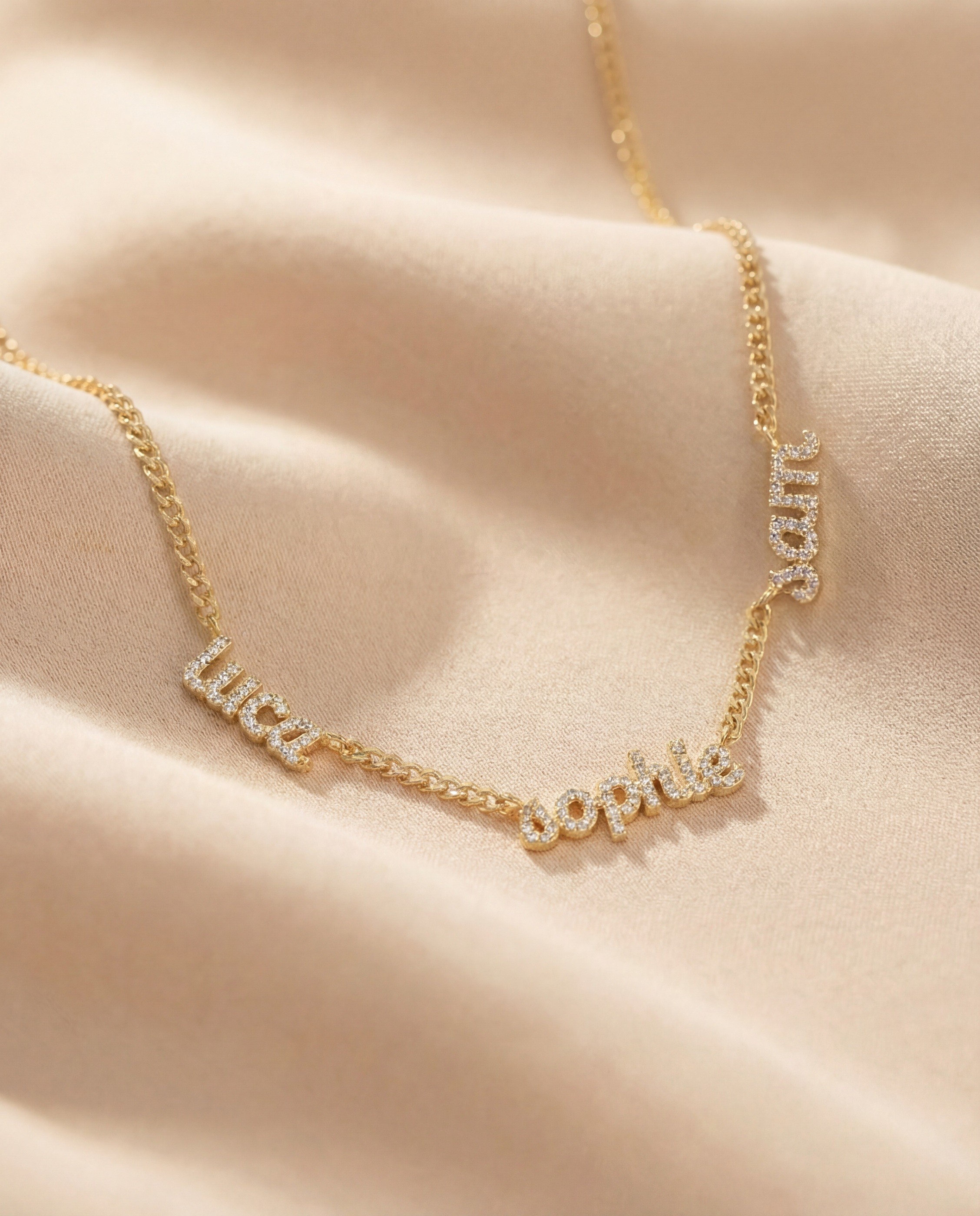 Vedder & Vedder — Personalized gold name necklace arranged over cream satin.