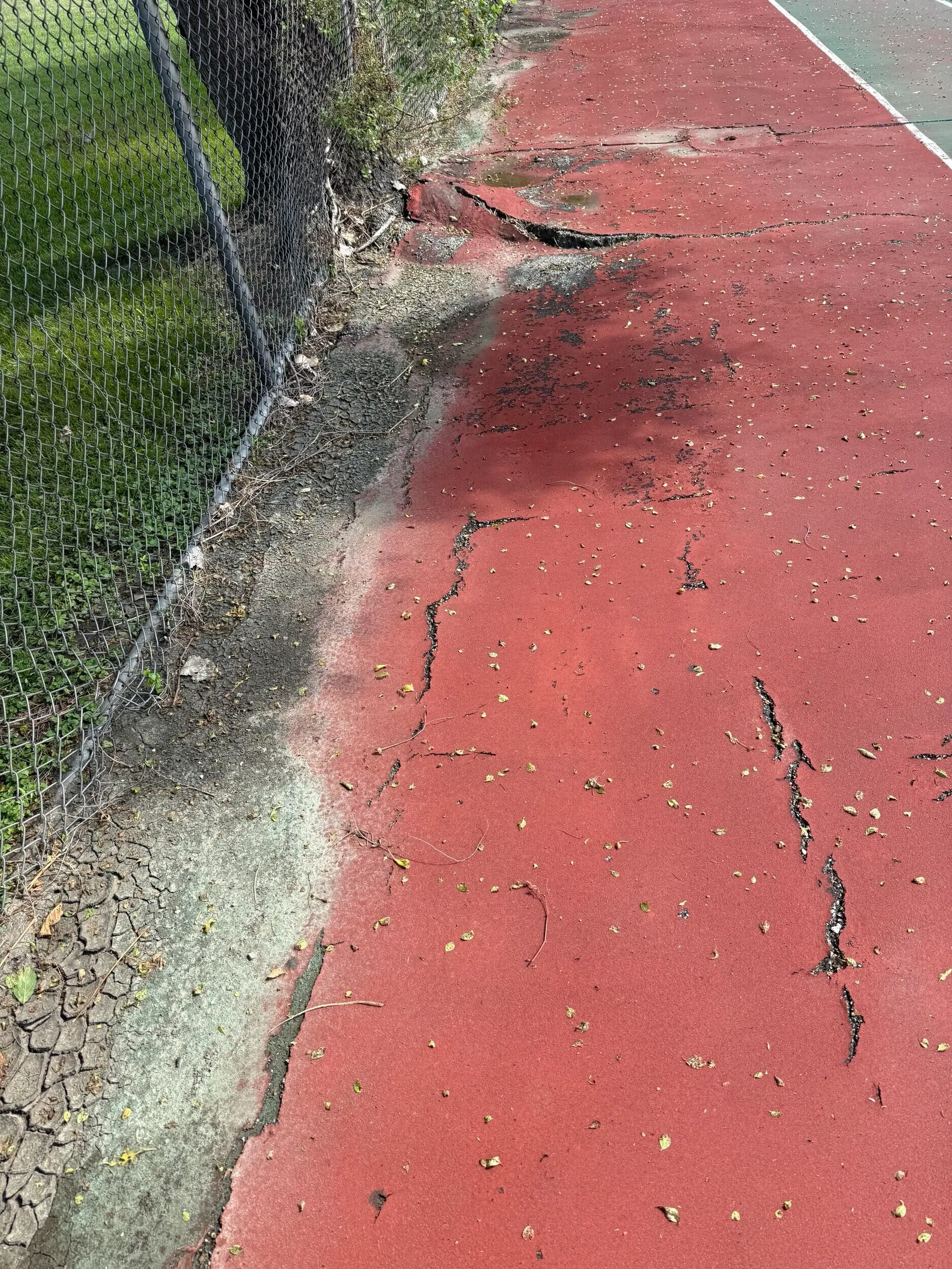 Cracked and deteriorated tennis court perimeter before resurfacing at Clintondale Community Schools