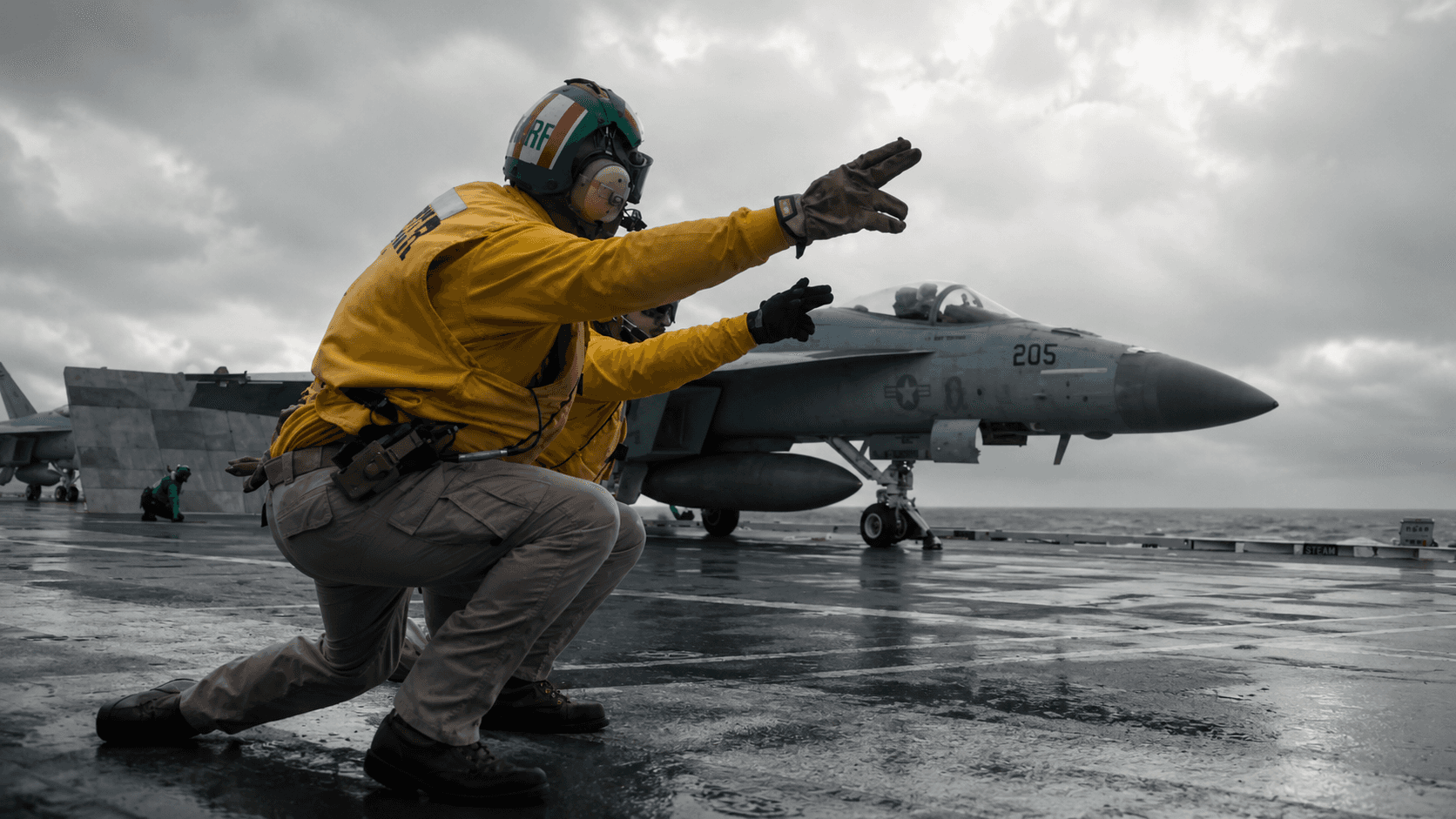 aircraft carrier navy servicemen signaling to jet for take off