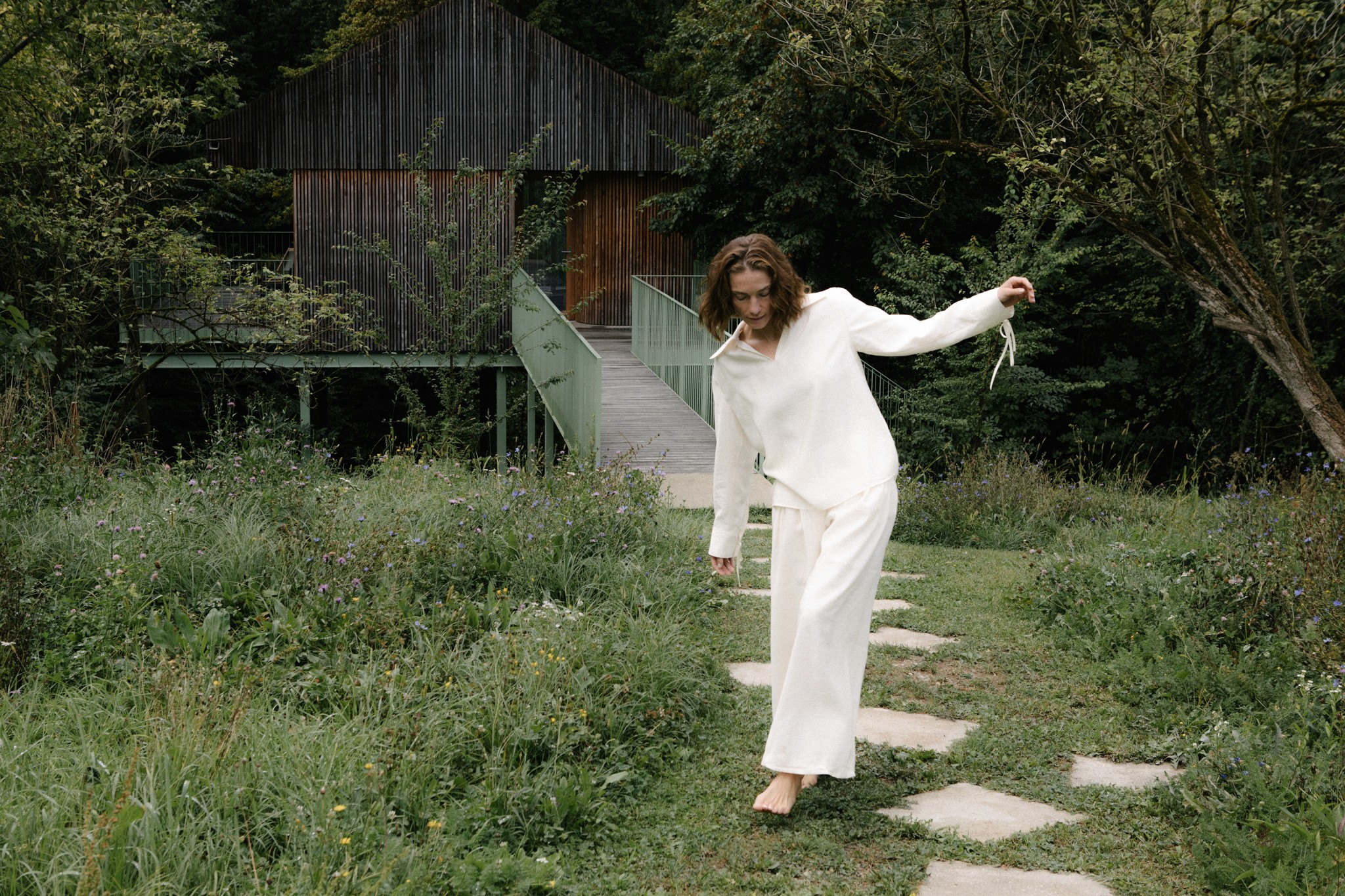 Frau geht barfuß über Steinweg im Garten vor modernem Haus