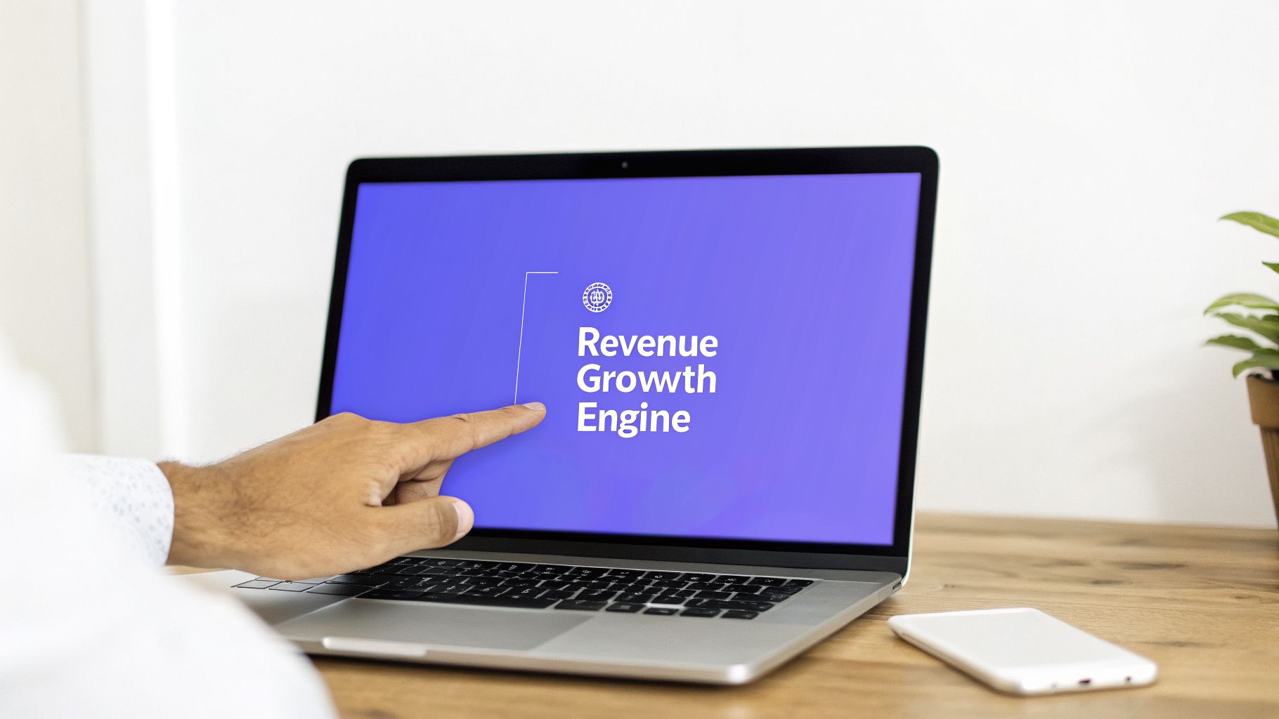 A hand points to a laptop screen displaying 'Revenue Growth Engine' with a logo, on a wooden desk.