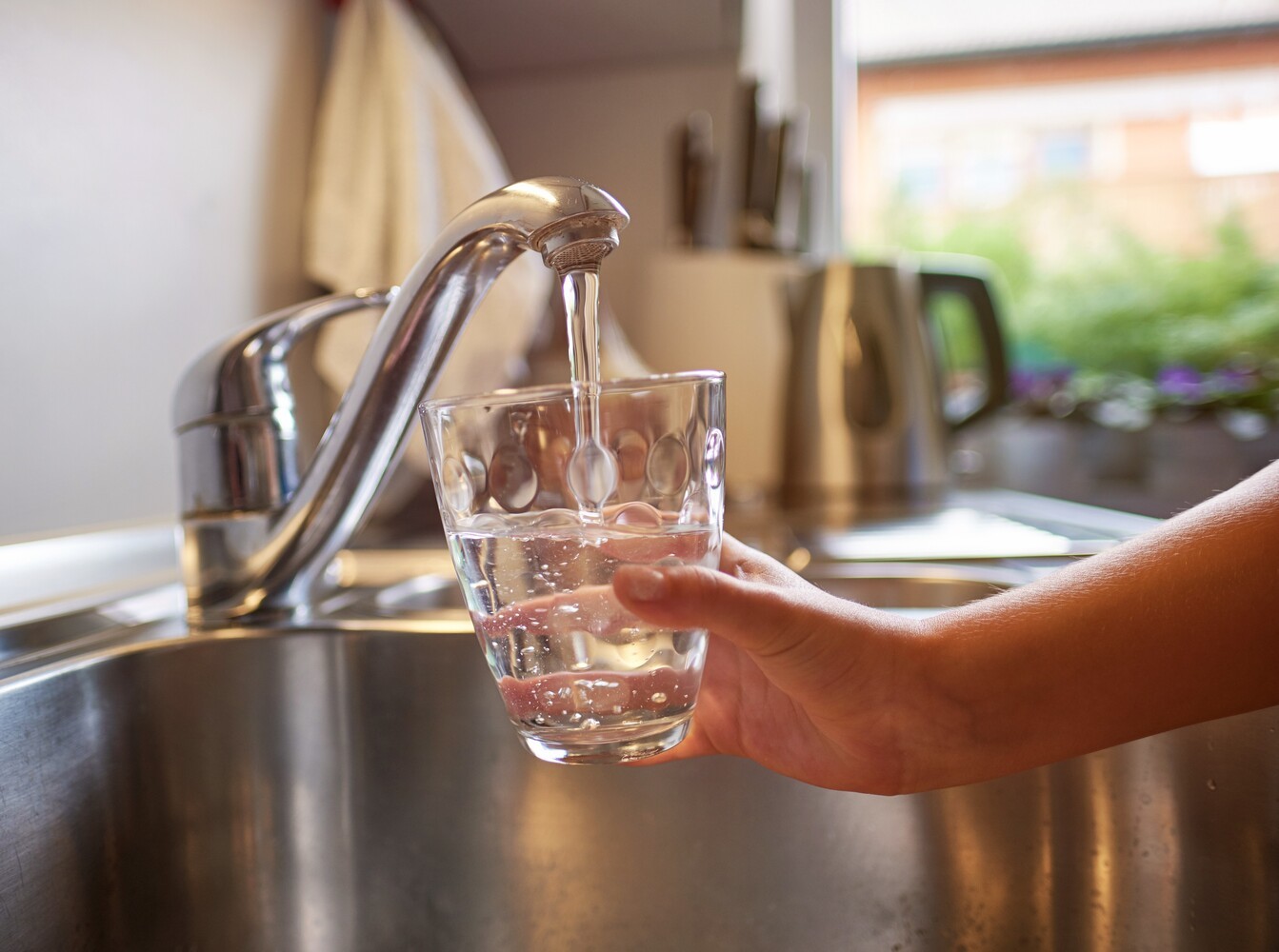 person pouring a glass of water to drink to improve their saunas and weight loss results
