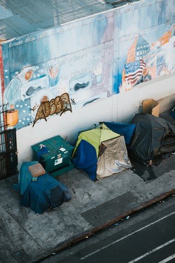 Four tents on a pavement next to a road.