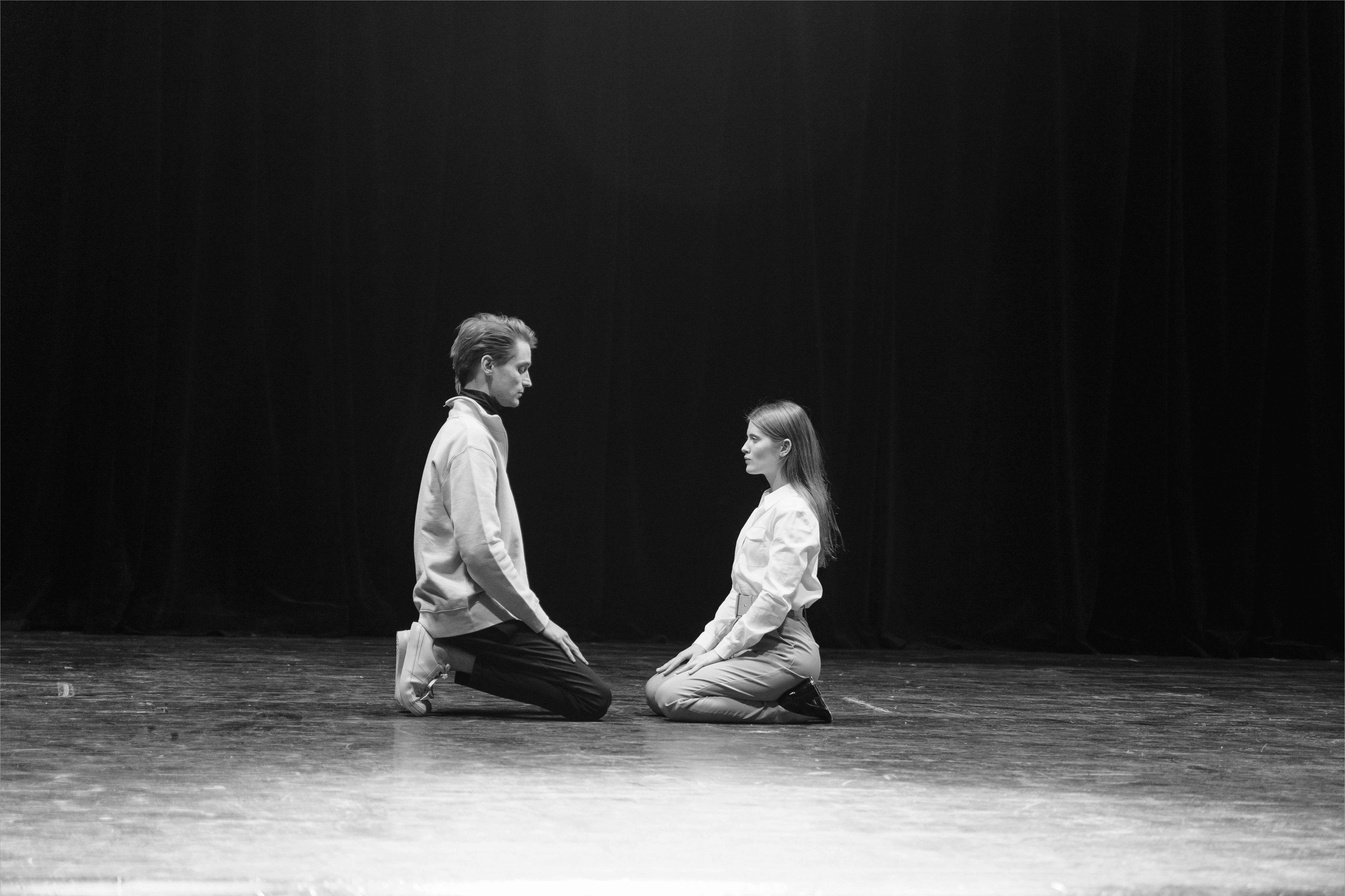 A wide shot of a man and woman facing each other on their knees