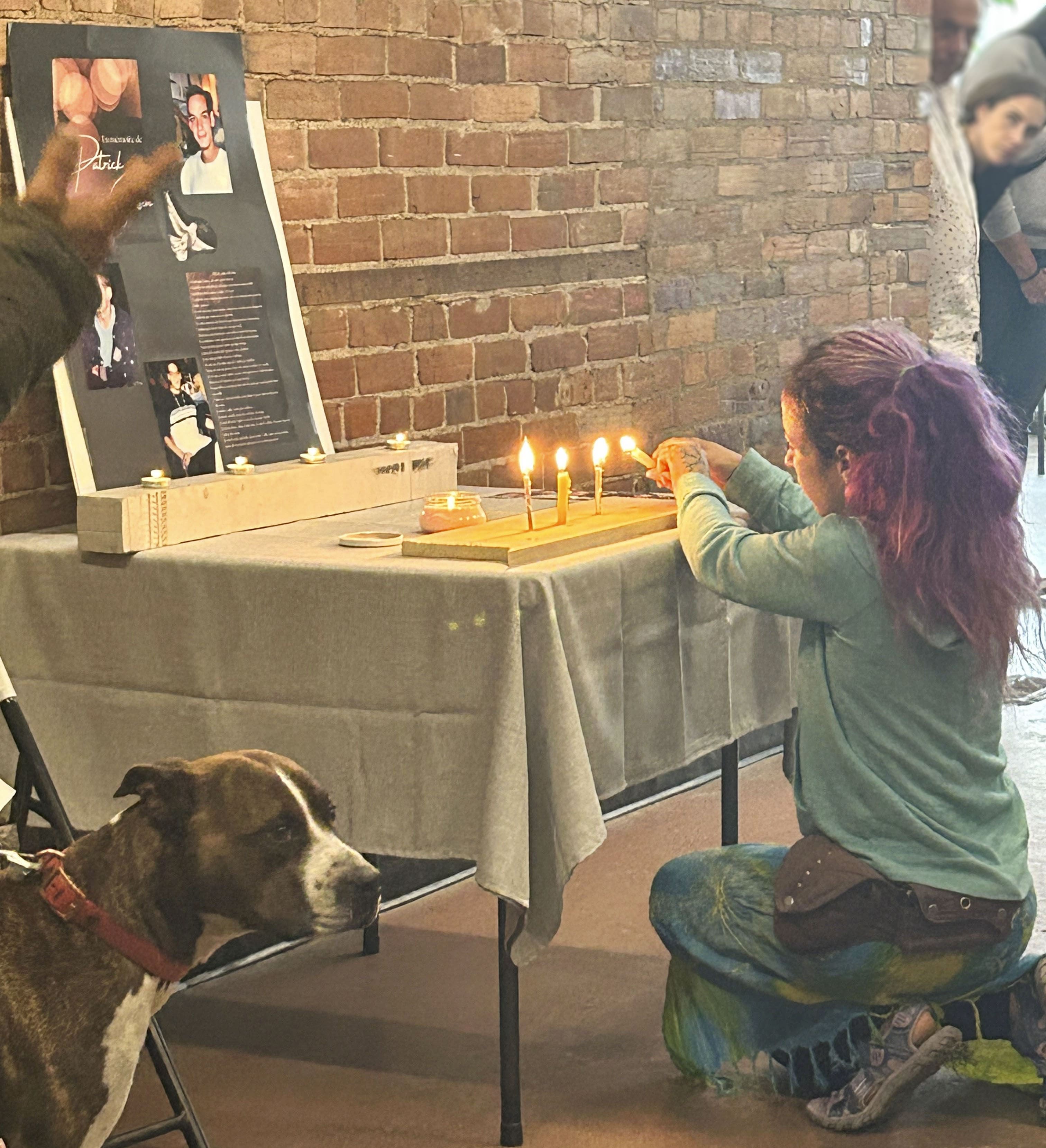 Personne allumant des bougies sur une table, accompagnée d’un chien, dans une ambiance calme et chaleureuse.