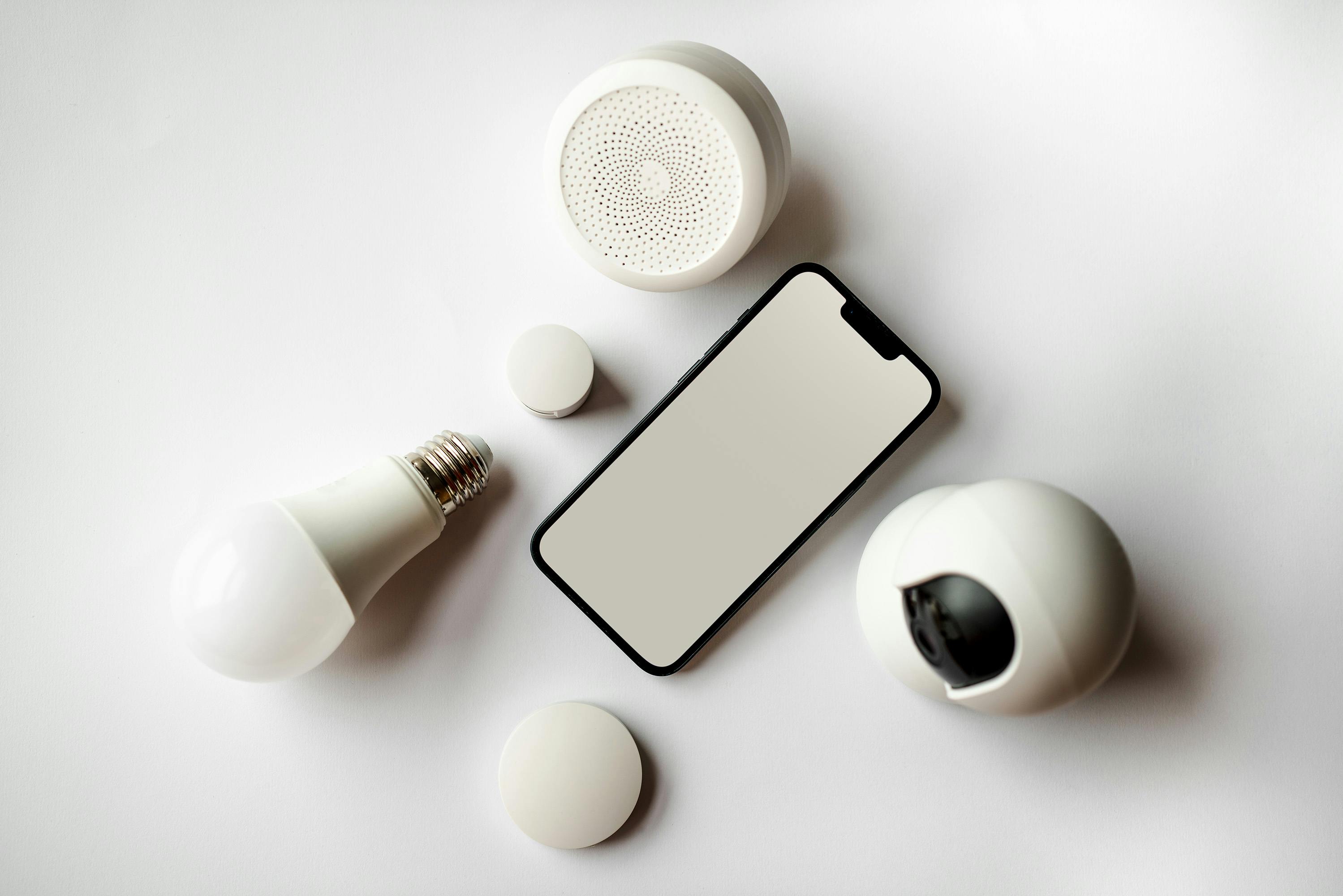 A phone on a white surface and is surrounded by dim lights, a camera, and a speaker.