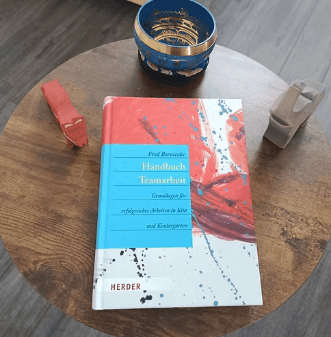 Buch "Handbuch Teamarbeit" mit Details, Kindergarten-Thema auf Holz Tisch.  Herder Verlag