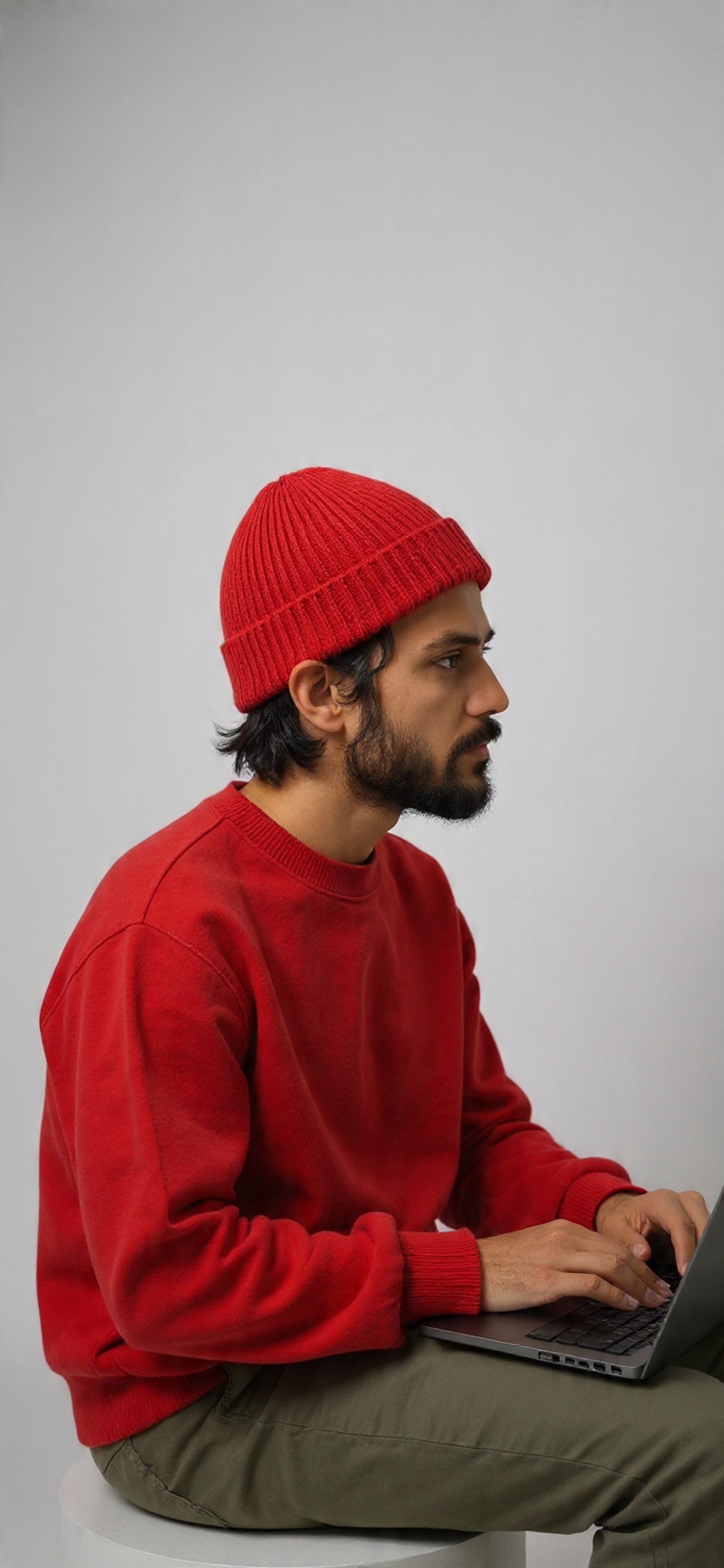 A man with long hair is working on a computer.
