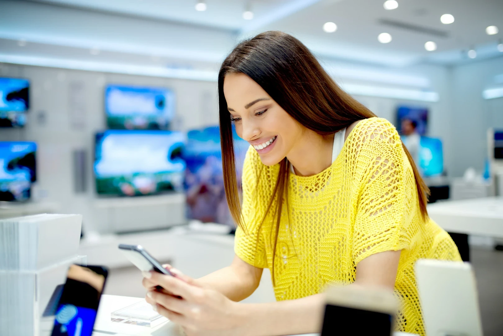 Mujer mirando un celular en un local de electrónica