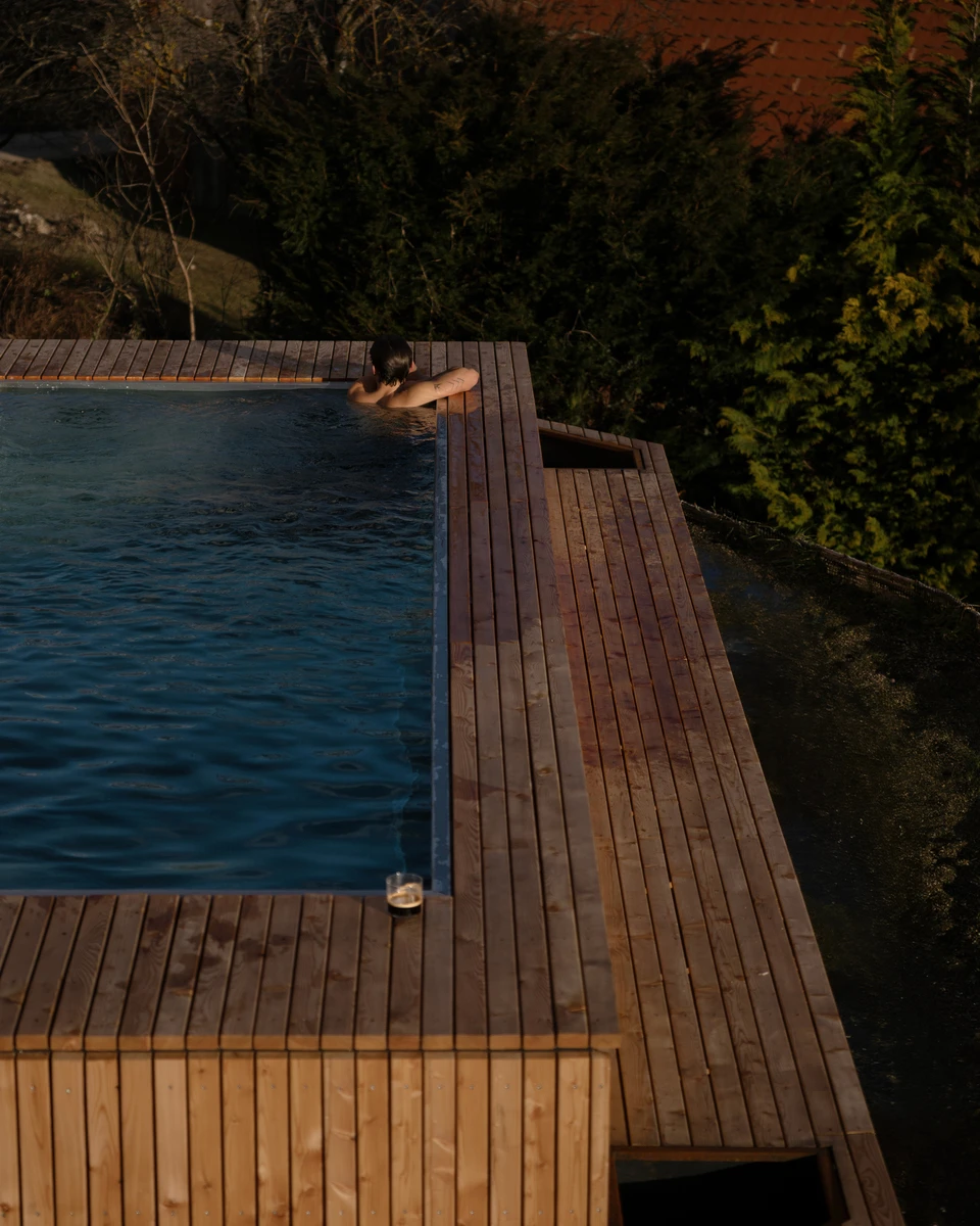 Blick von oben auf den Infinity-Pool und die Holzterrasse des Chalets in Weinitzen bei Graz
