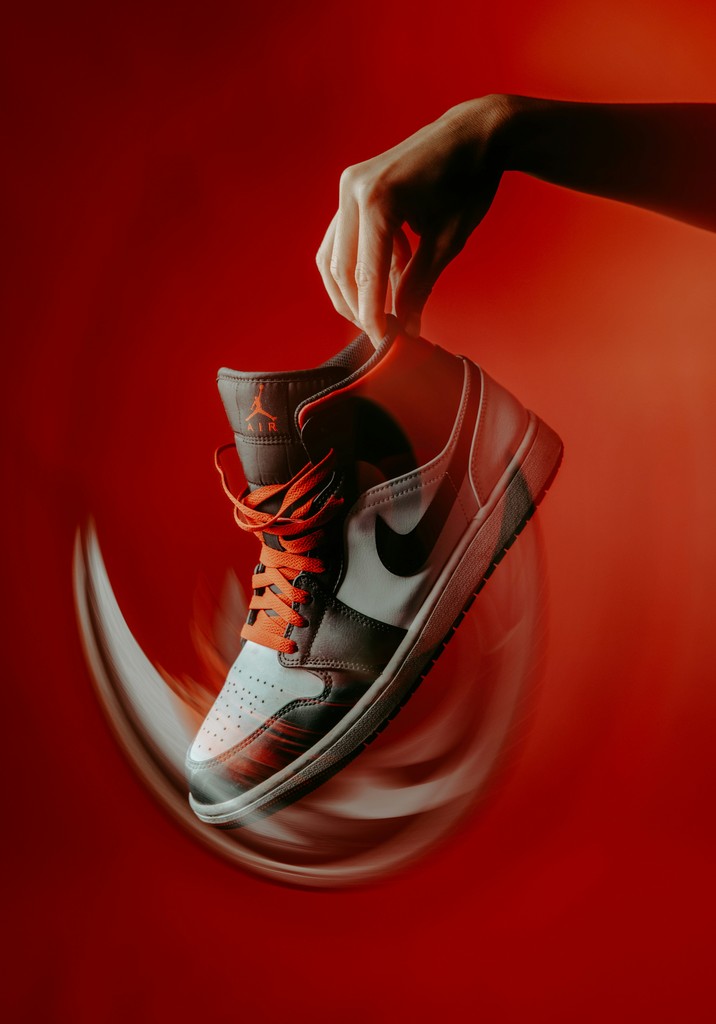 Hand holding a spinning sneaker against red background