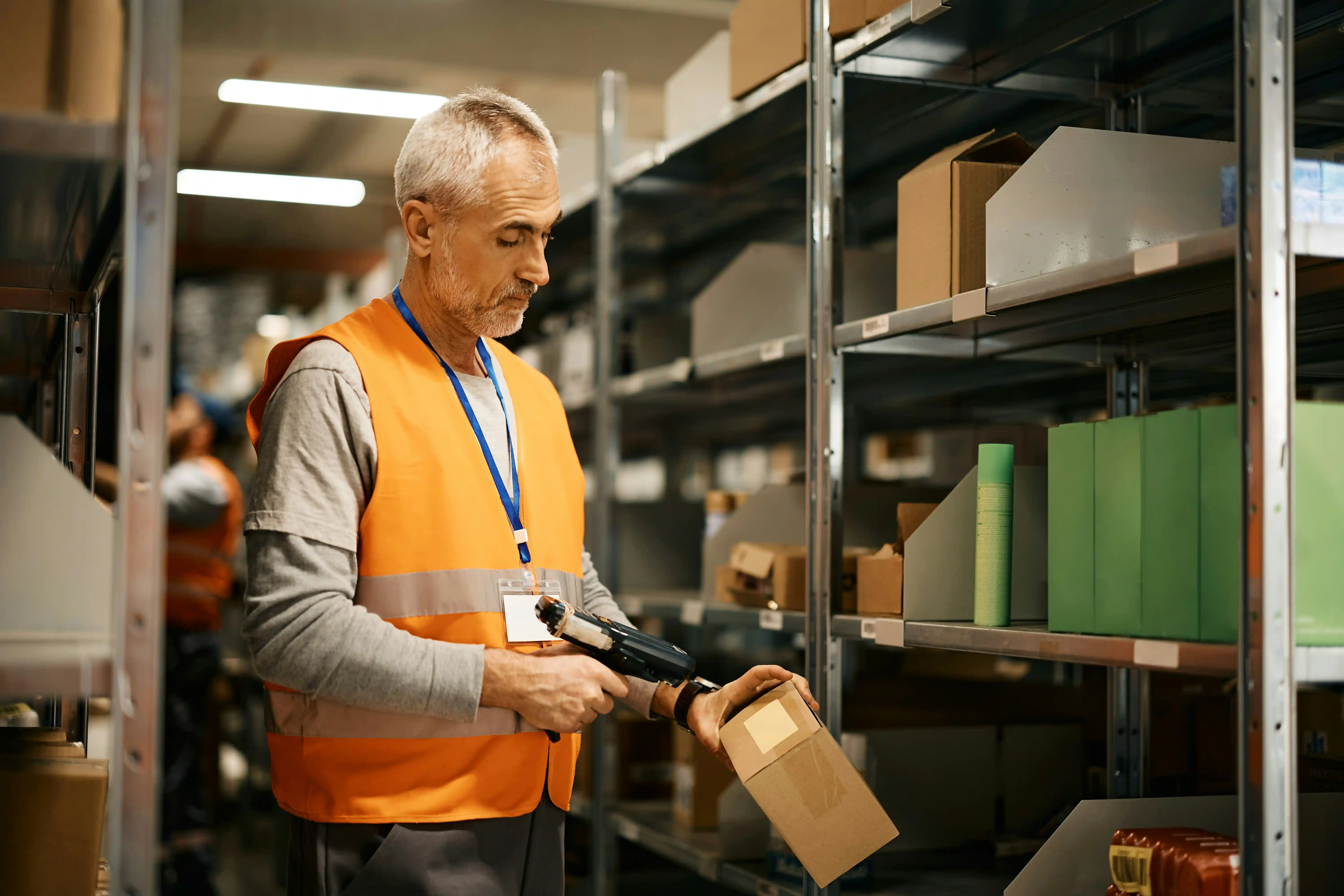 warehouse worker in orange high-vis jacket scans a parcel