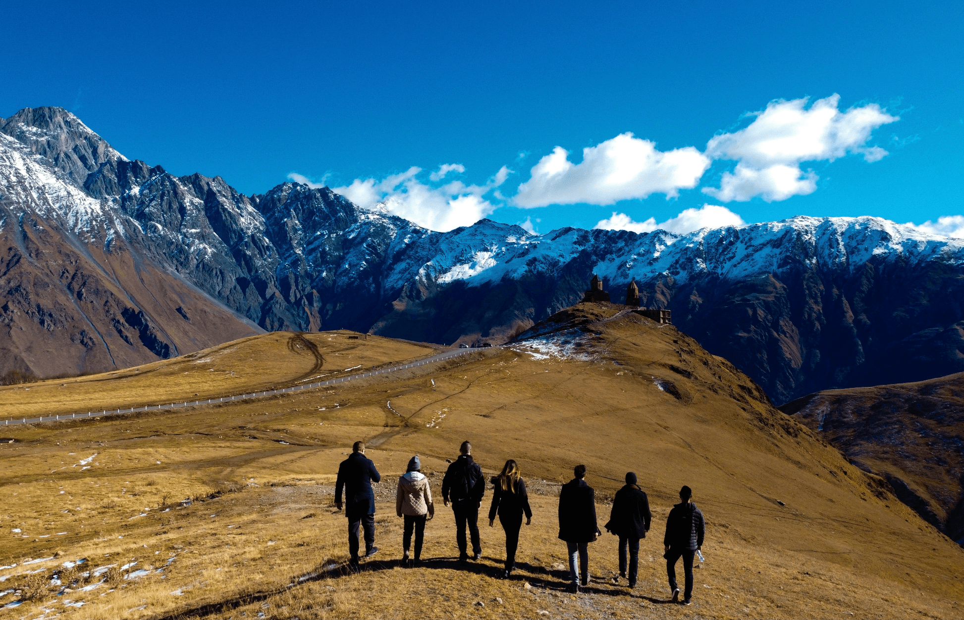 group of people standing on brown field near snow covered mountain during daytime