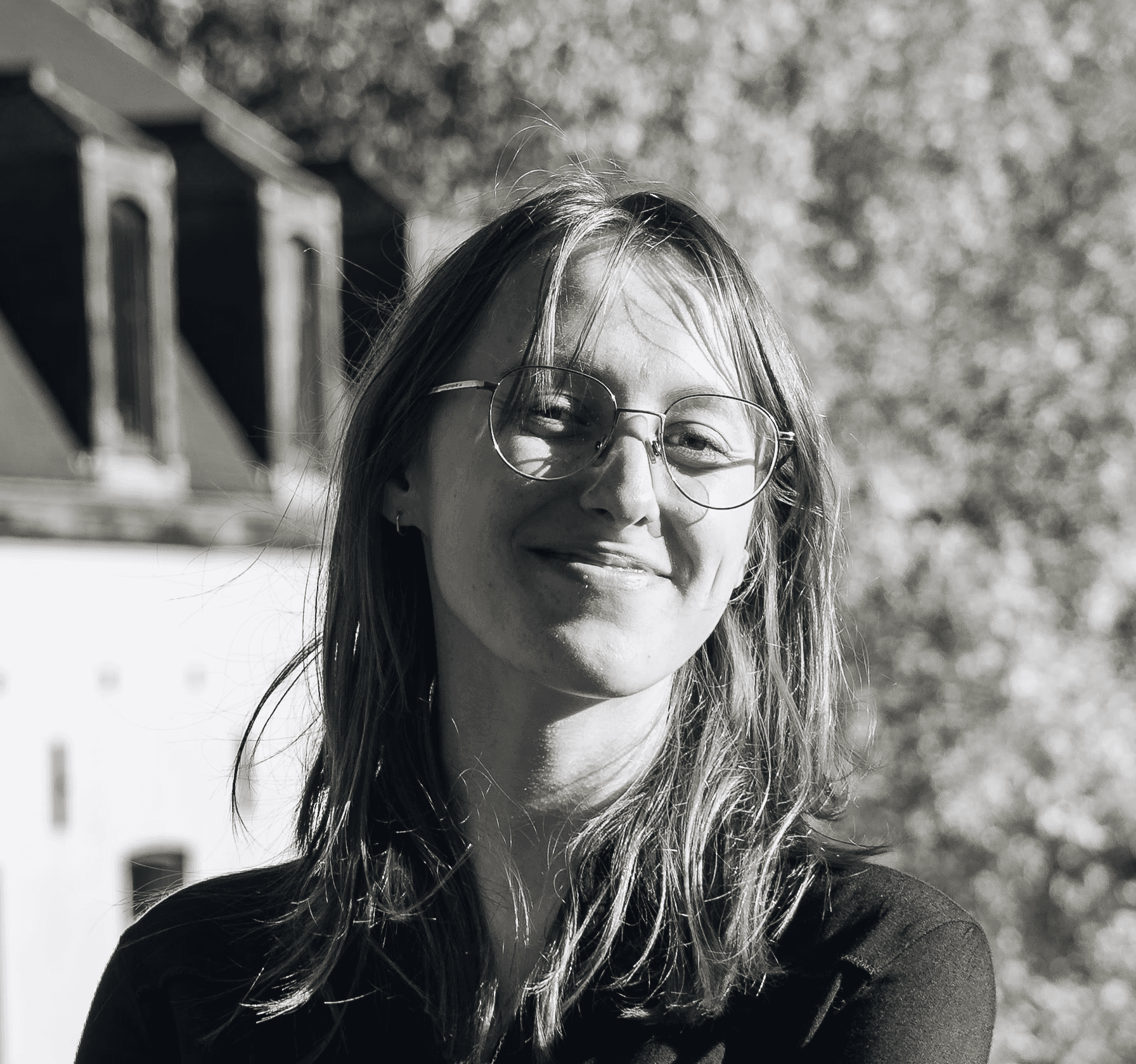 Portrait of a laughing person with curly hair wearing a white shirt