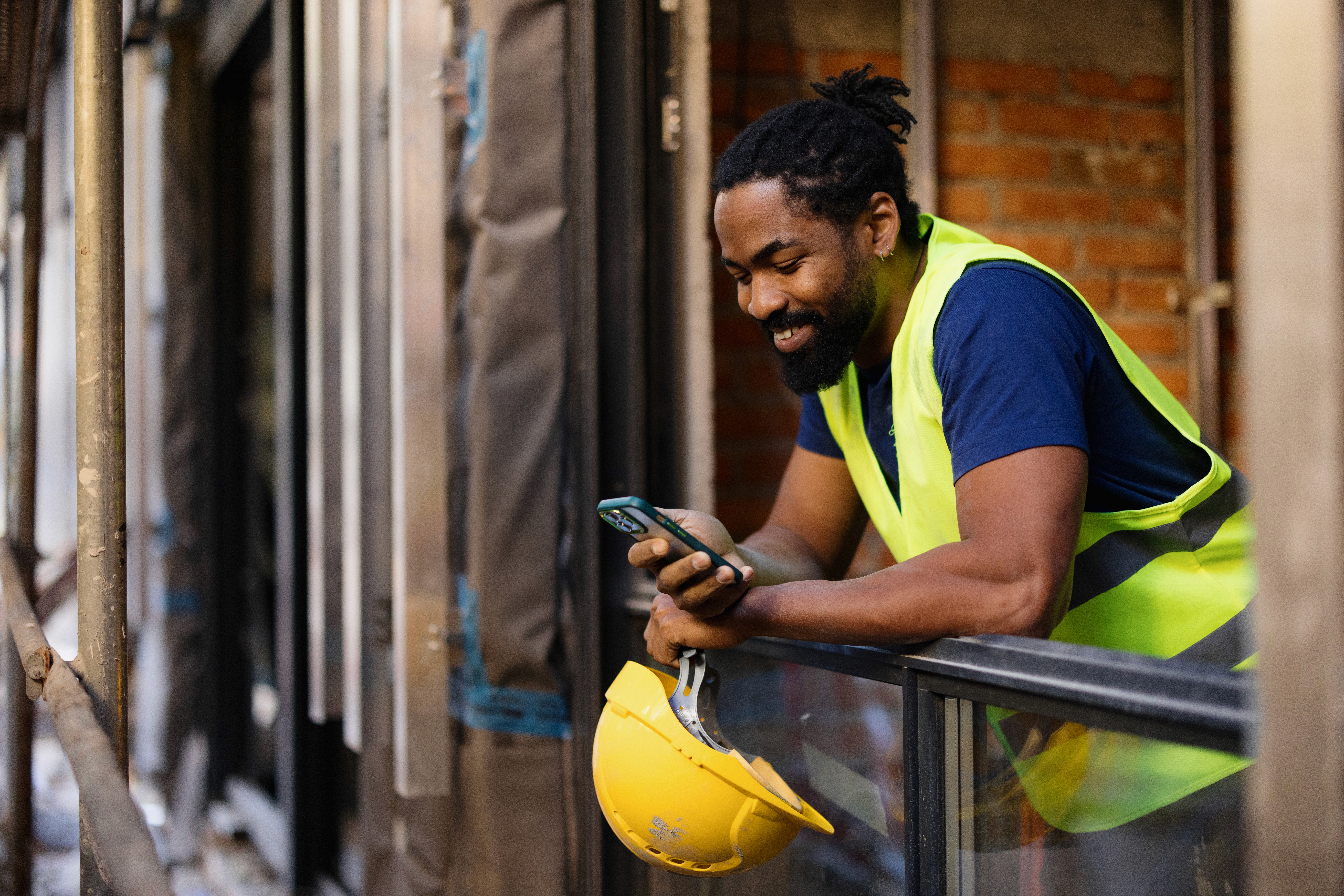 Tradesperson taking a break on a construction site while checking messages on their phone