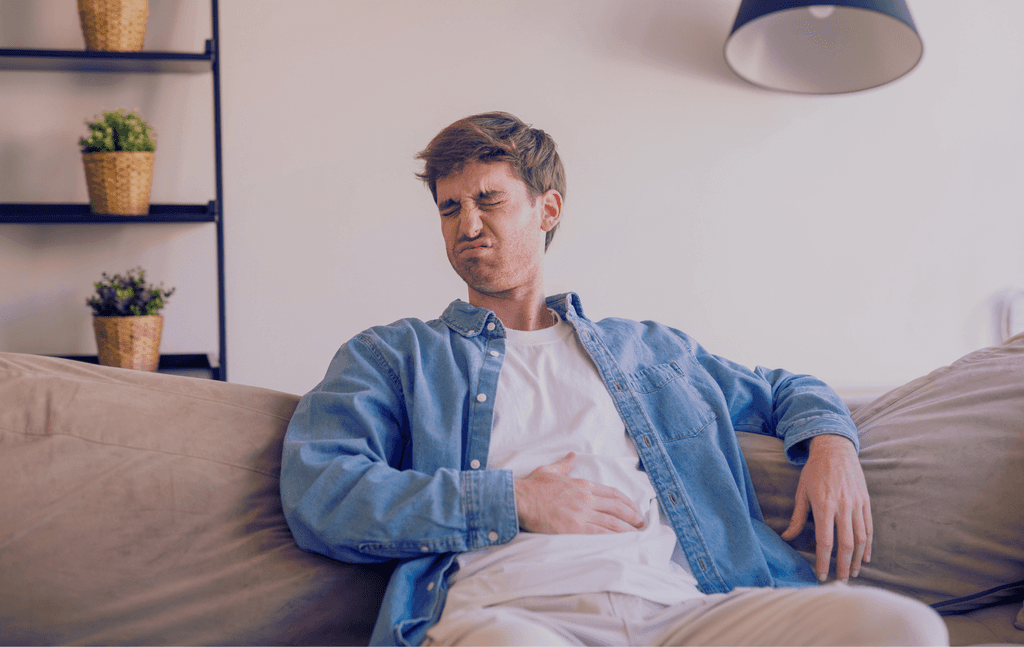 Persona con sensación de hinchazón y pesadez abdominal después de una comida abundante.