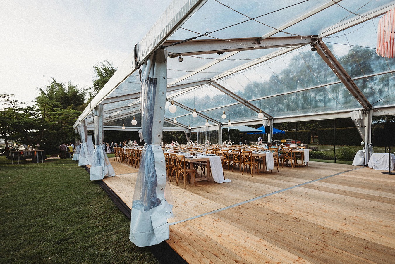 Outdoor table setting under a clear roof marquee