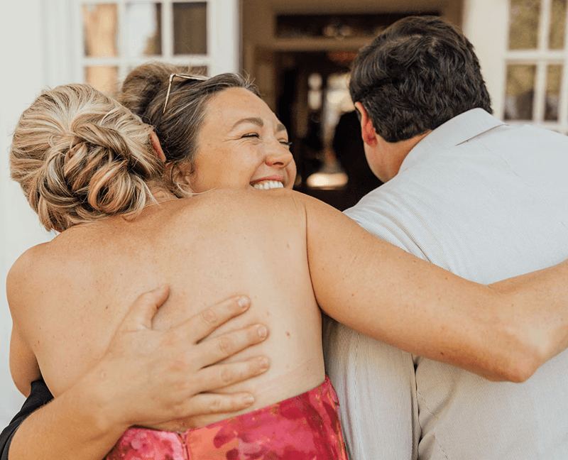 Father and mother of the bride hugging wedding planner at Berry College in Georgia