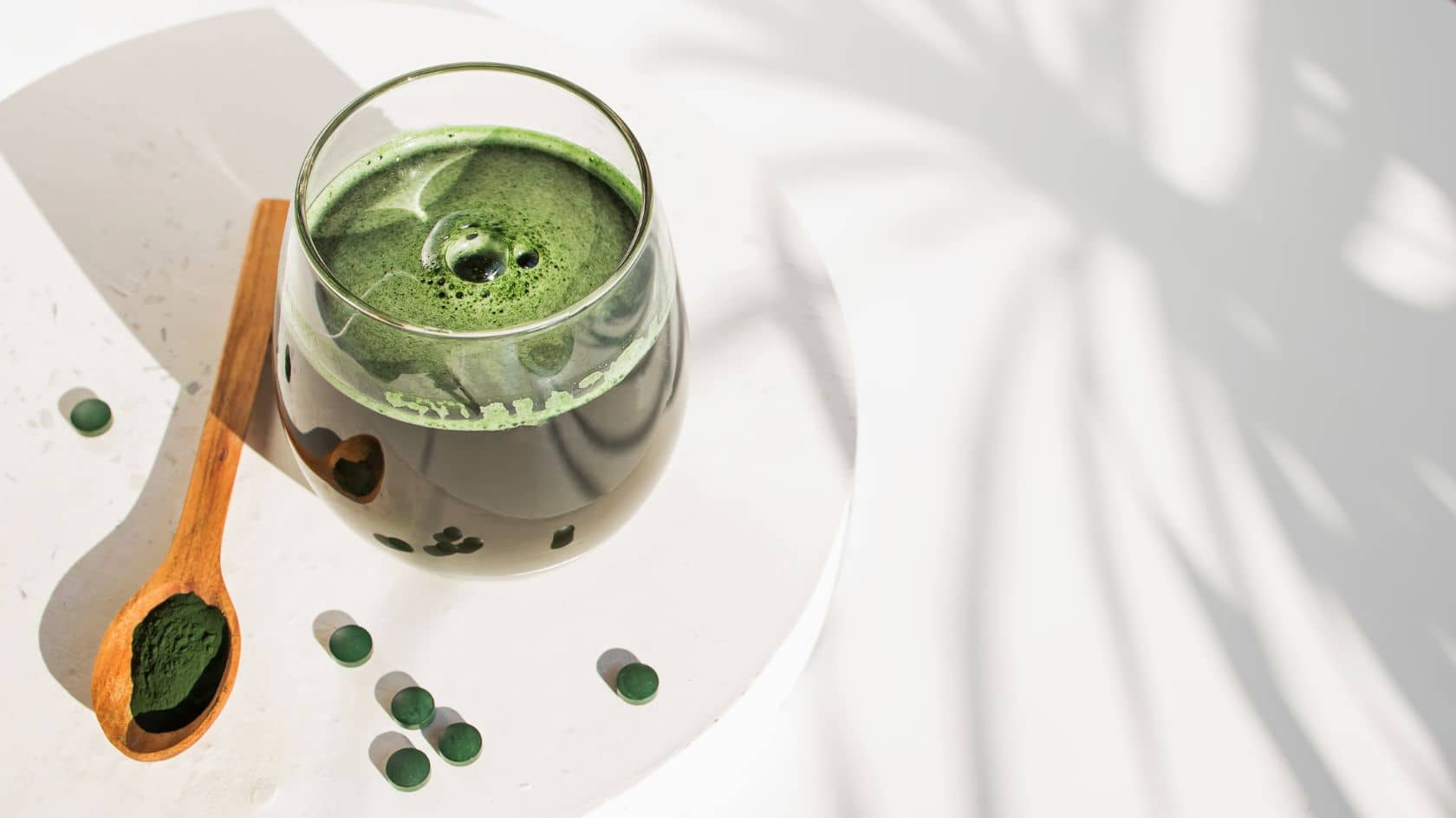chlorella powder alongside a glass of water mixed with chlorella